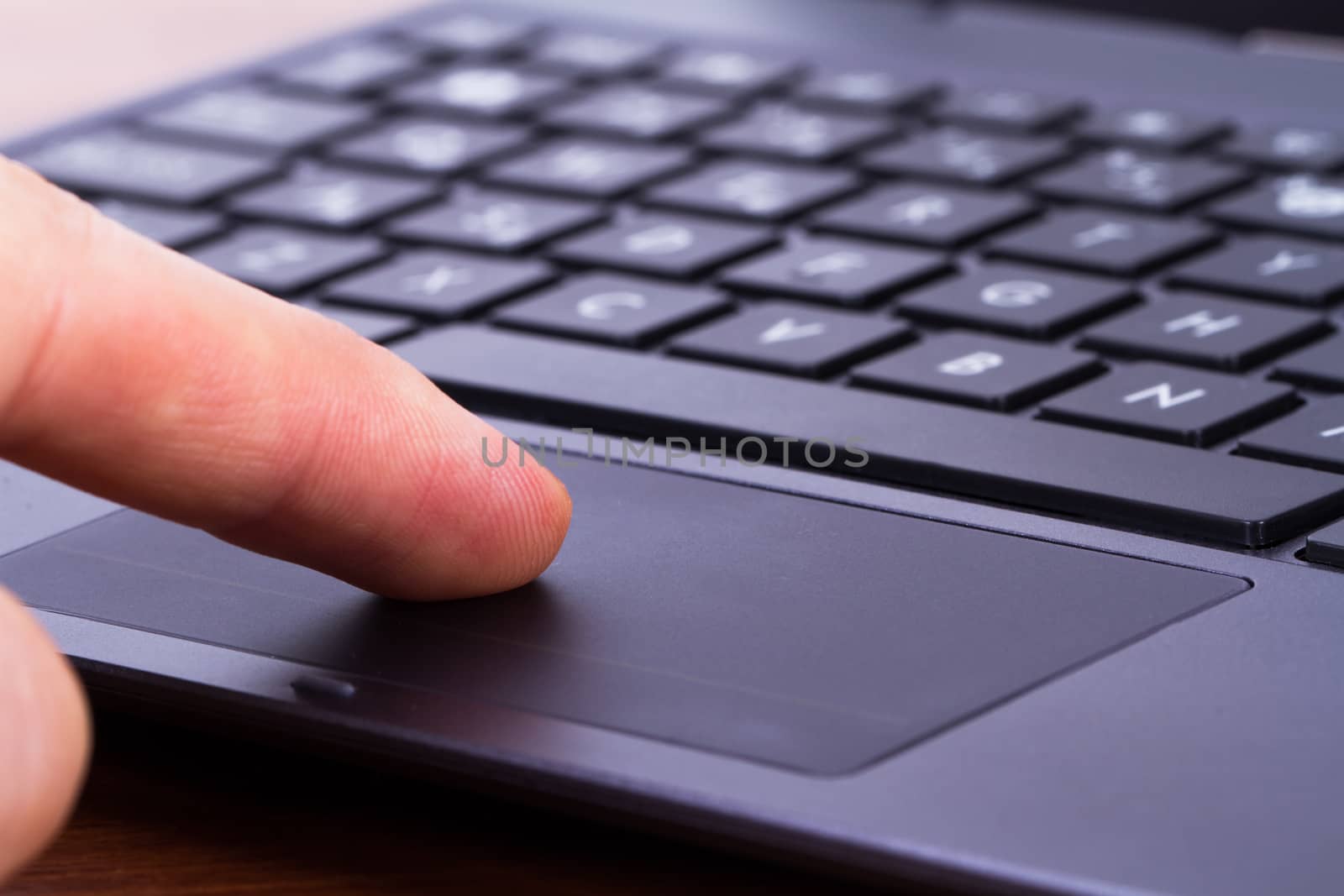 Index finger touching touch pad on laptop keyboard.