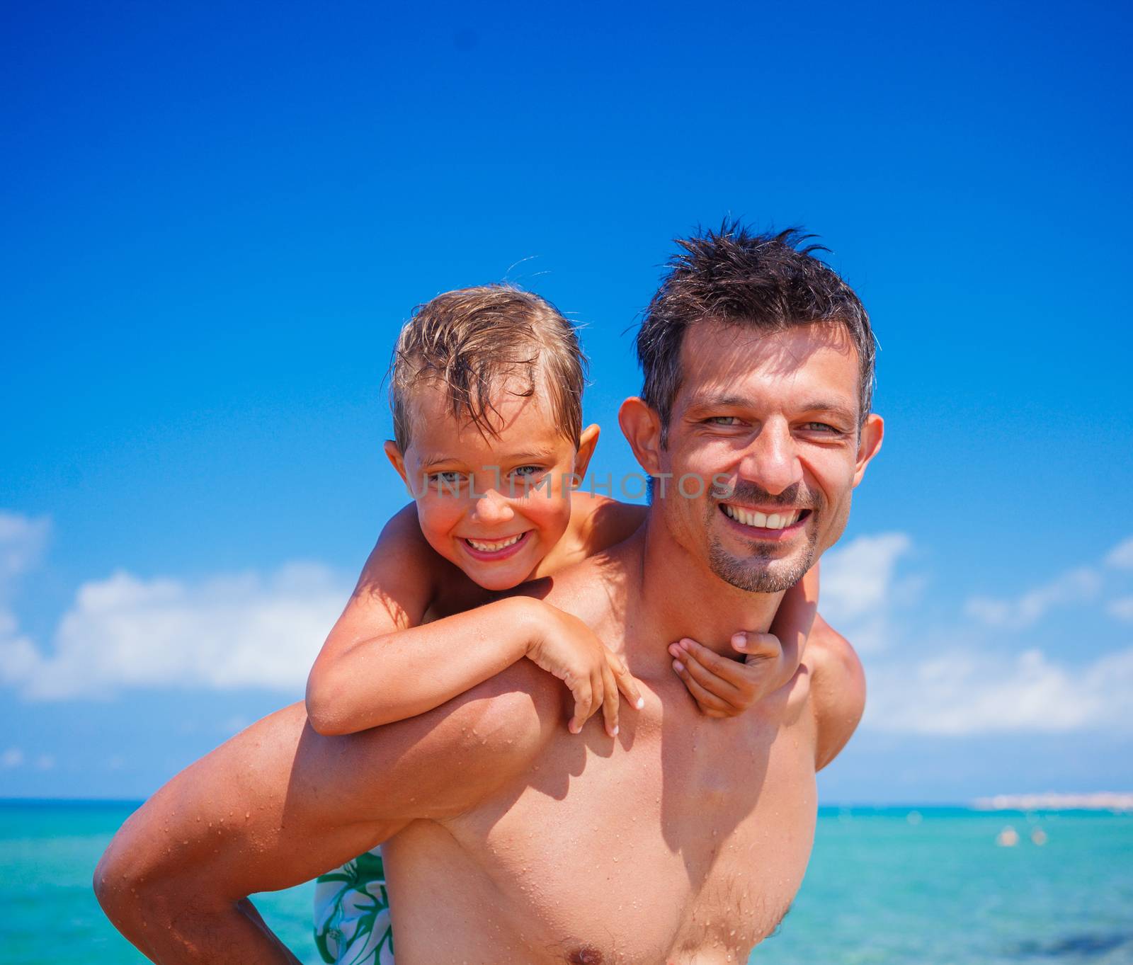 Father holding son on his shoulders at the beach