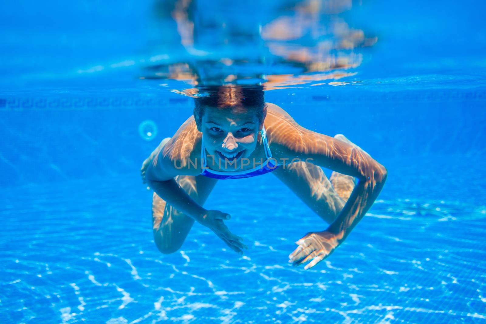 Portrait of underwater happy cute girl in swimming pool