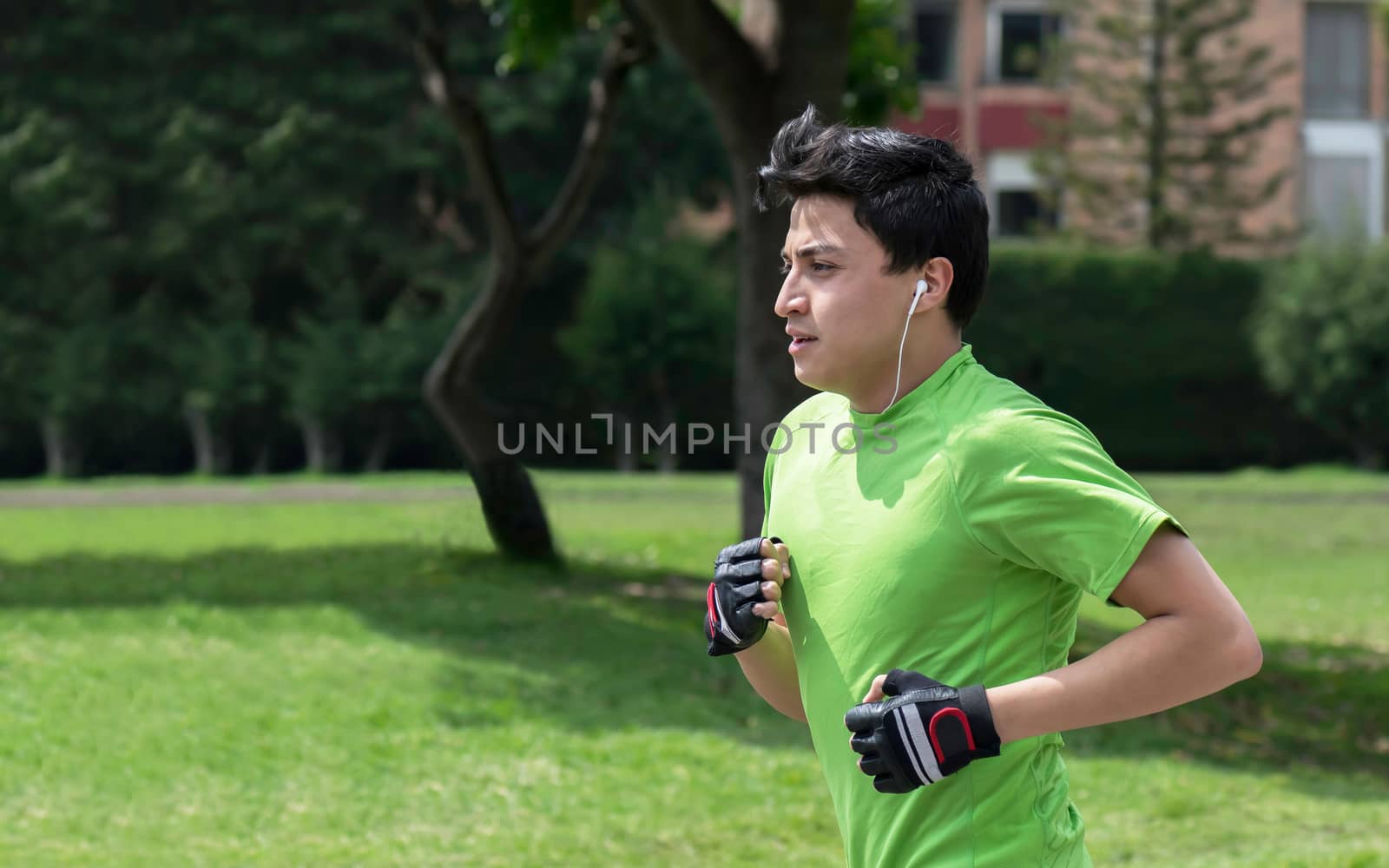 Young man at a local green park jogging 