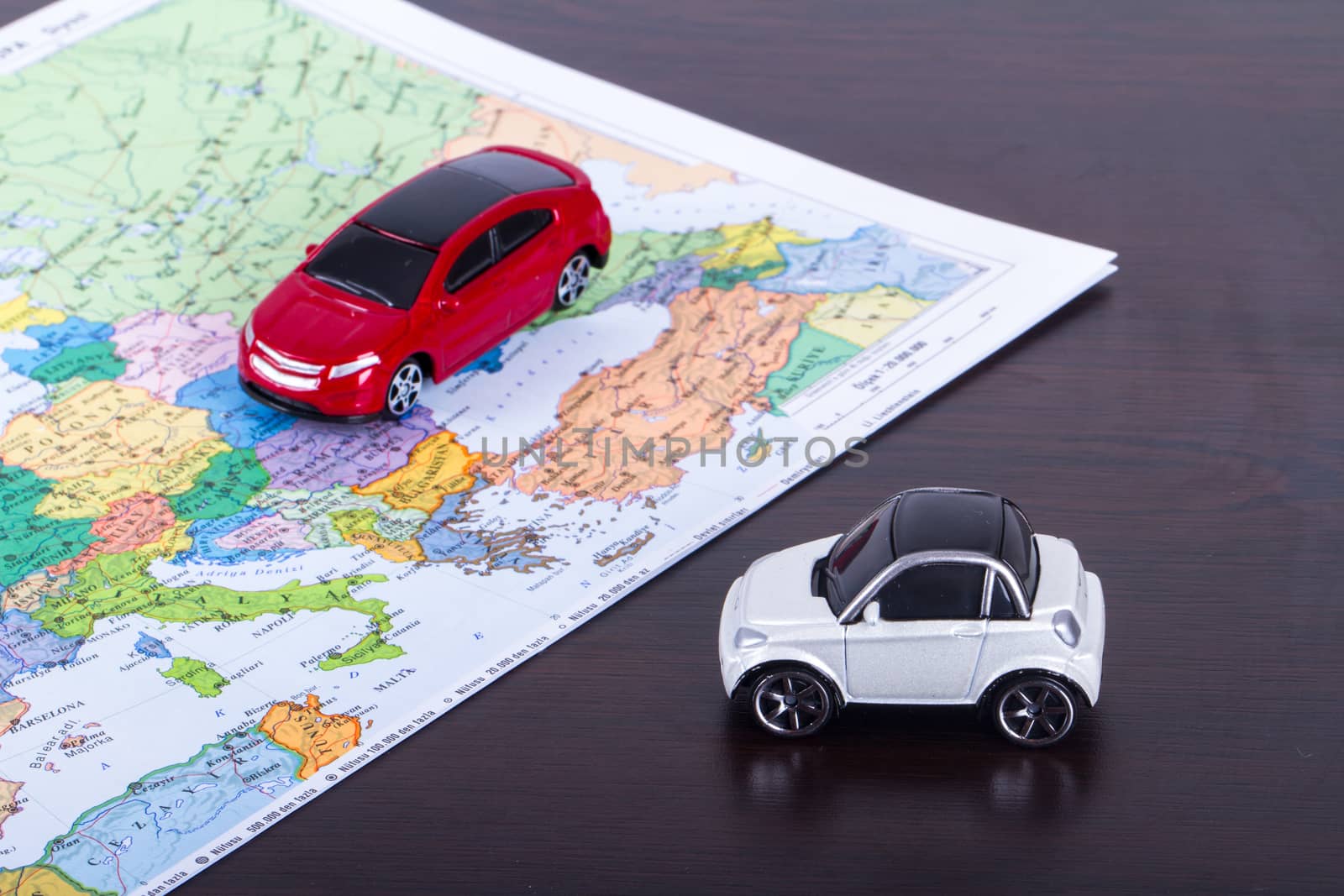 Small, toy car for travel concept on colorful map.