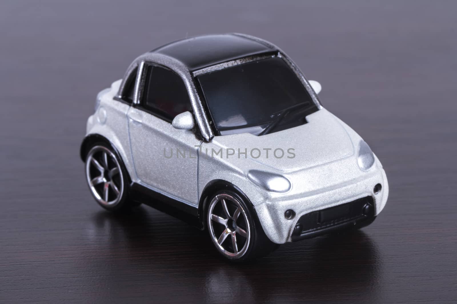Side view of white, toy, small car on wooden table.
