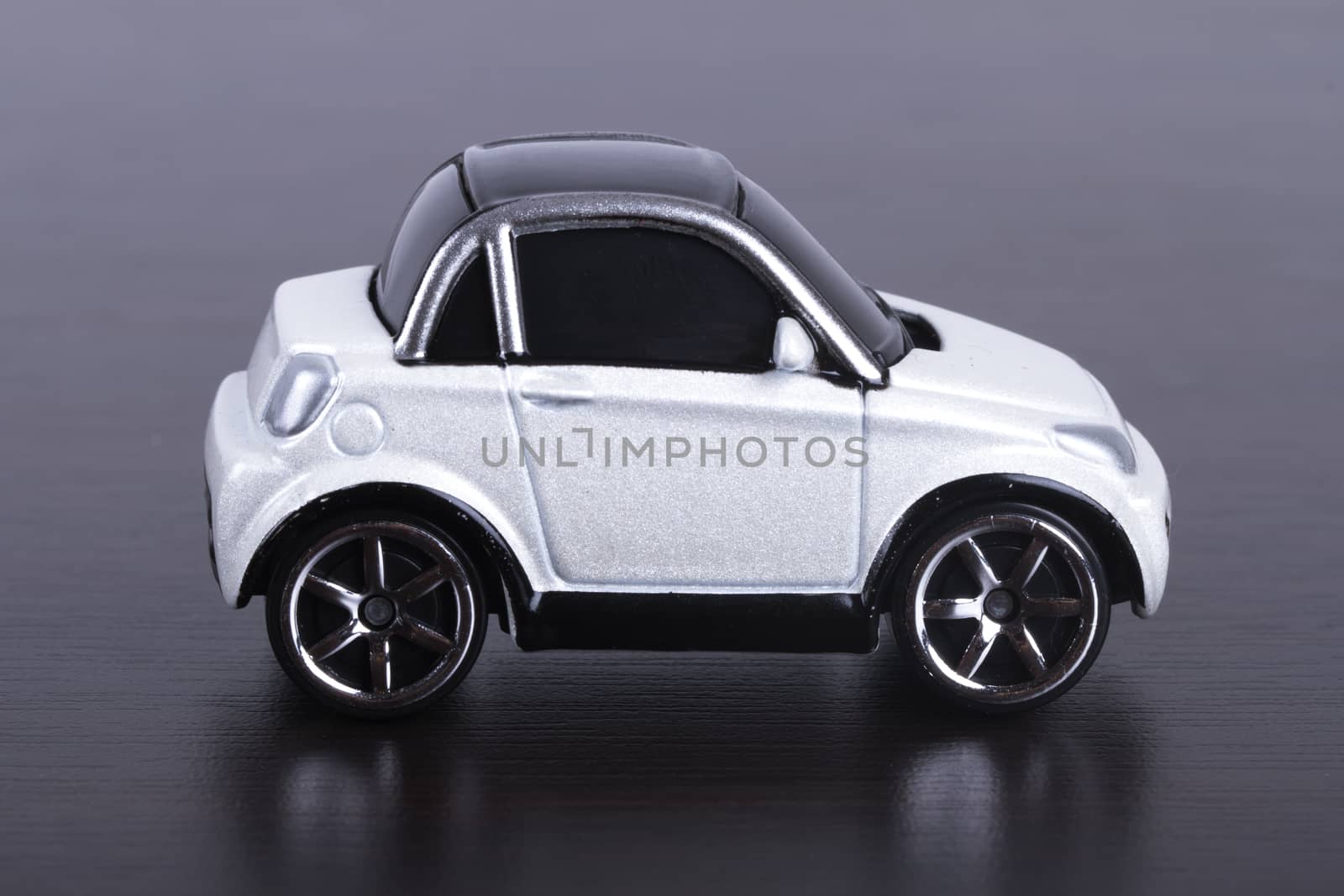 Side view of white, toy, small car on wooden table.