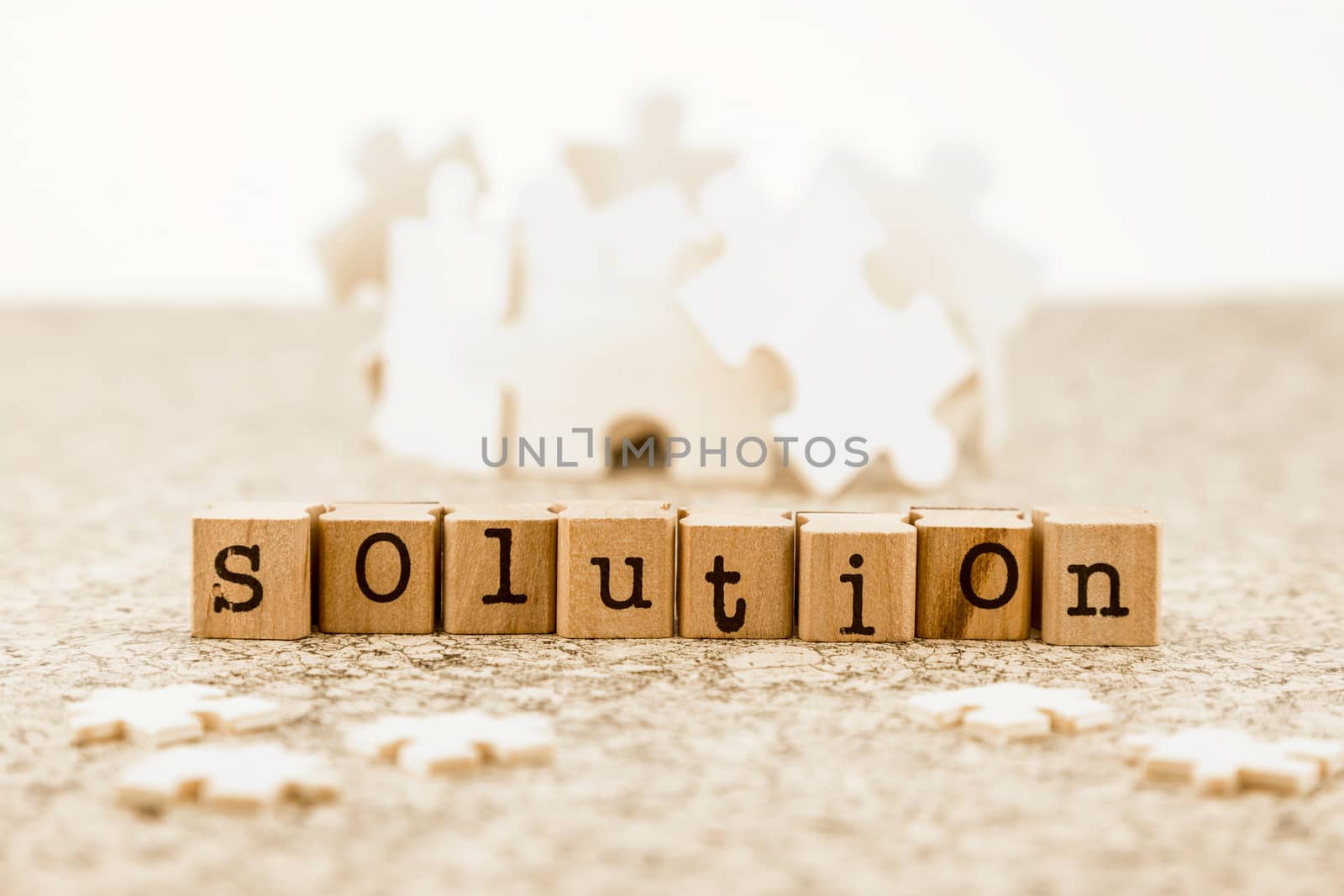 The word solution on wood stamps with little jigsaw pieces on foreground and group of large jigsaw pieces on background, idea of problem solving with brainstorm possible solutions