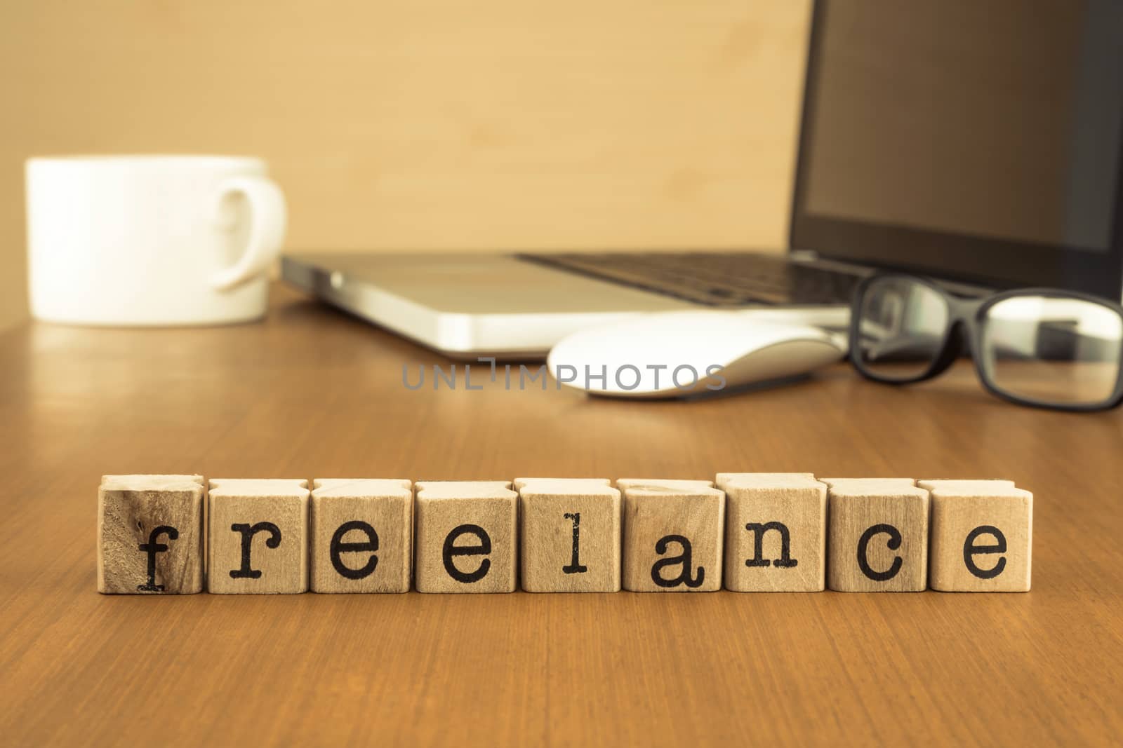 The word freelance on wood stamp stacking on desk with laptop, glasses and a cup of coffee at home office, vintage retro image style