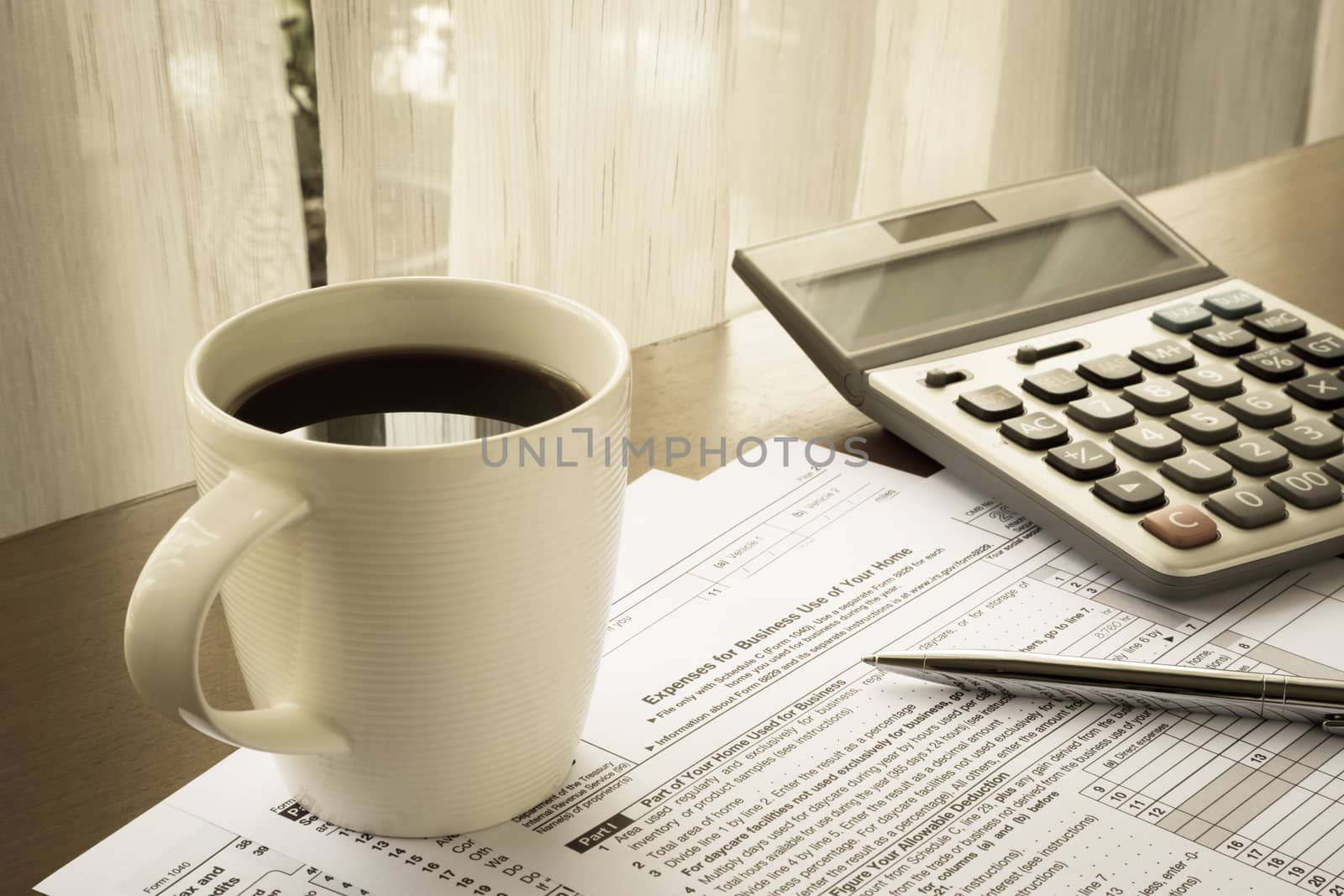 Tax forms of expenses for business use of your home place on home office table with a cup of coffee, calculator and pen