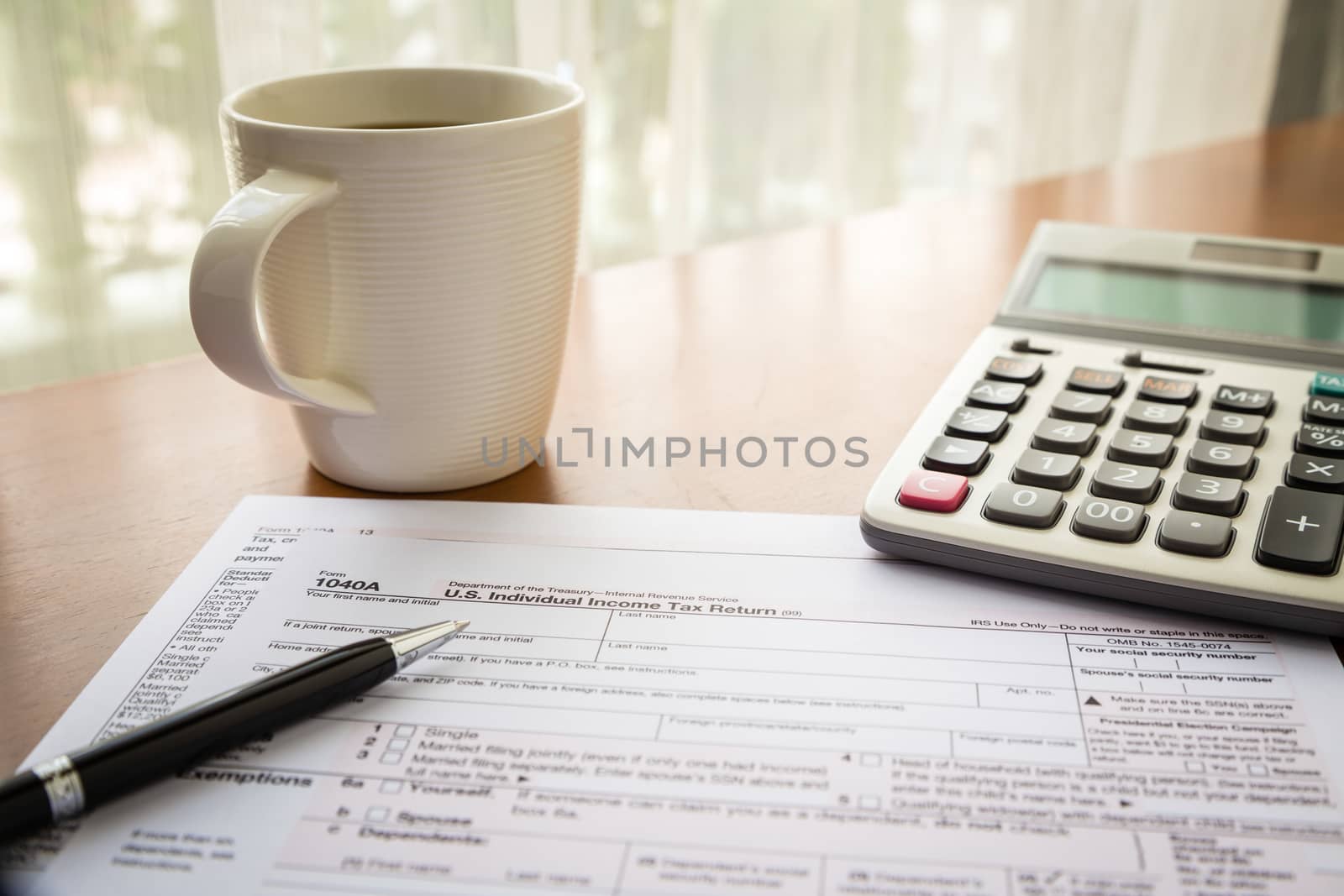 Form 1040A, U.S. Individual income tax return place on table with a cup of coffee, calculator and pen