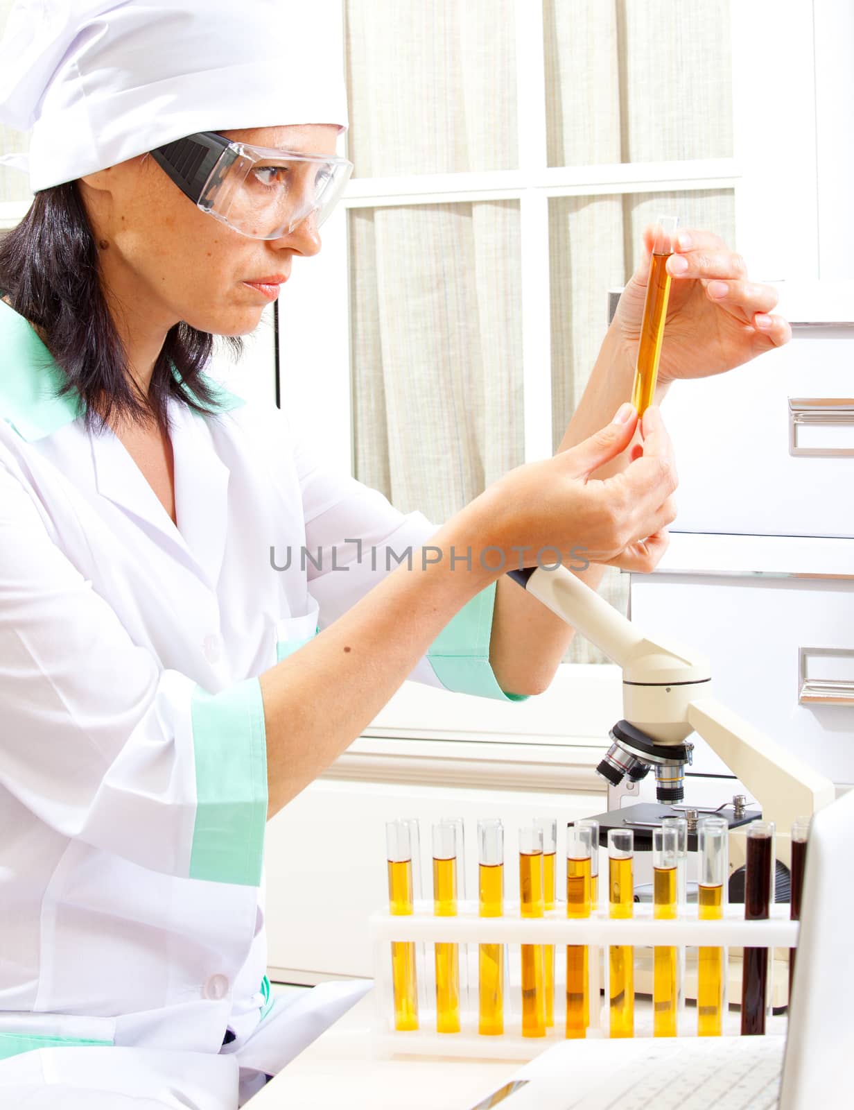 female scientist considering the sample tube in the life science research laboratory: biochemistry, genetics, forensics, microbiology