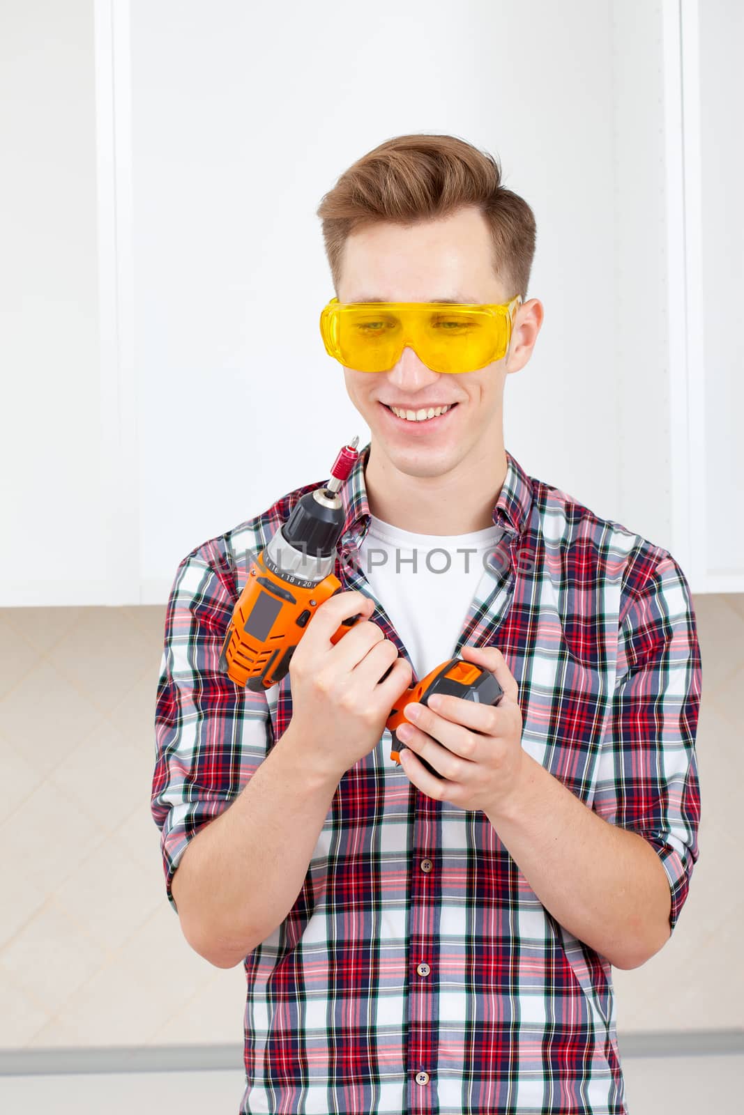 smiling repairman in eyeglasses and with a drill in his hands