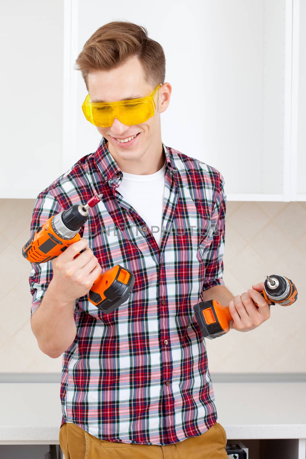 smiling repairman in yellow safety glasses selects tool by Astroid