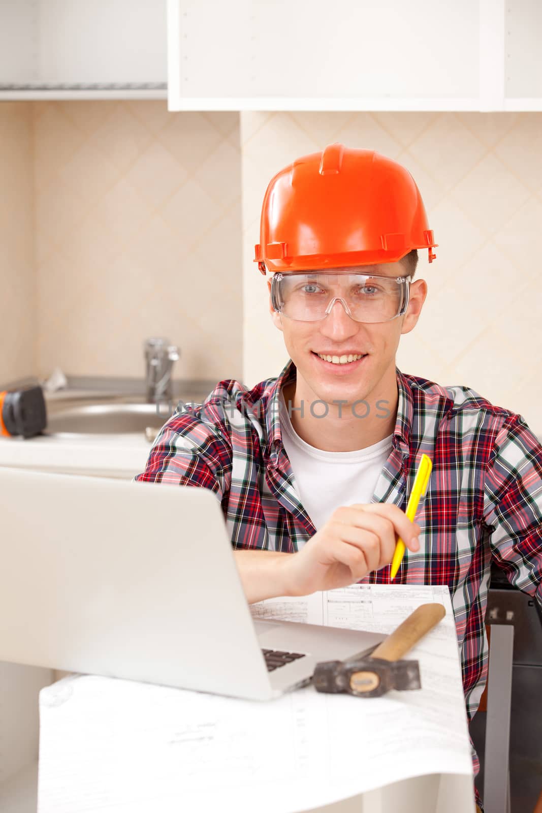 worker in protective helmet with a pen in hand and a computer on a desk on the workplace