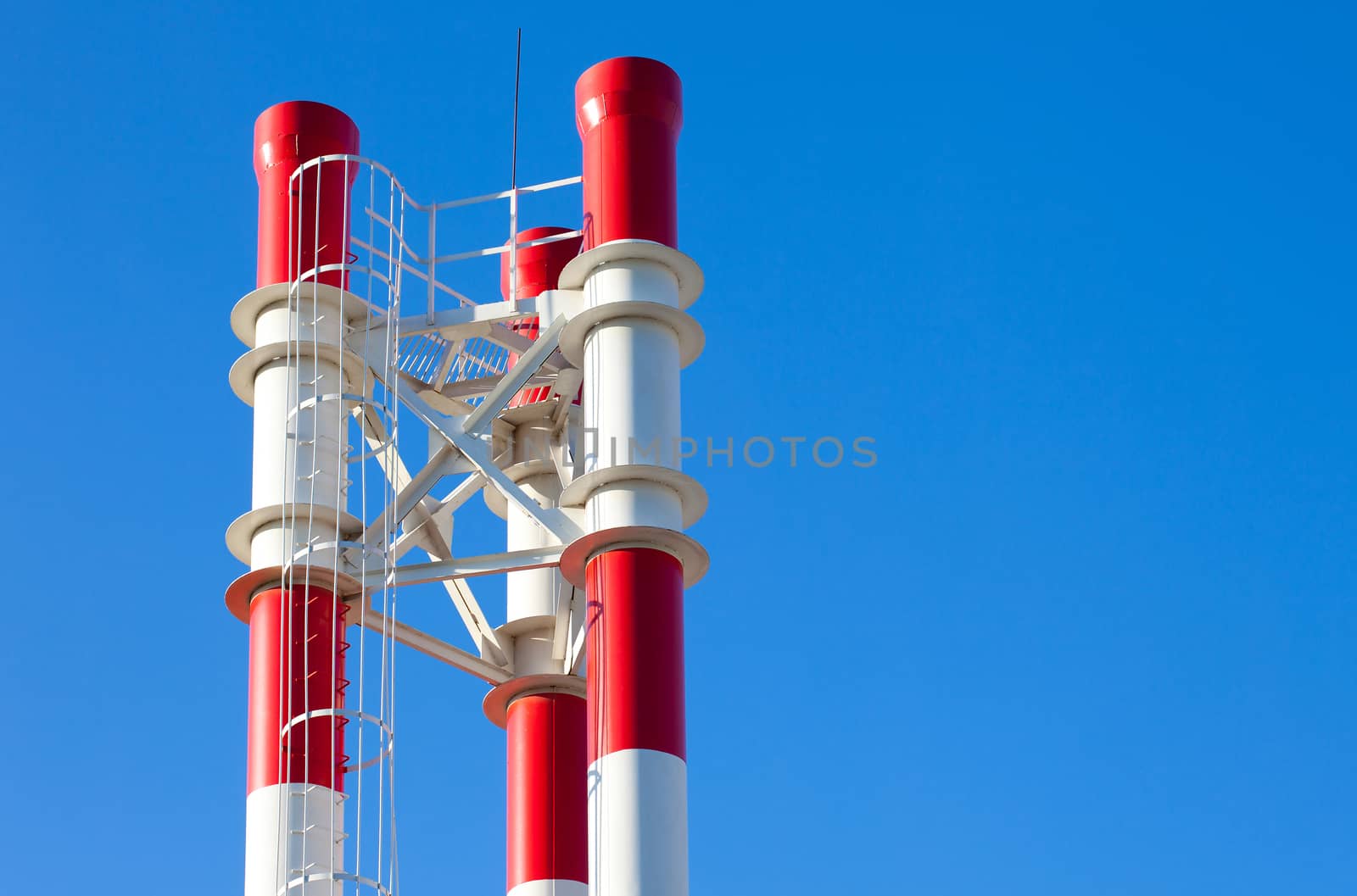 three red-and-white chimneys against the blue sky