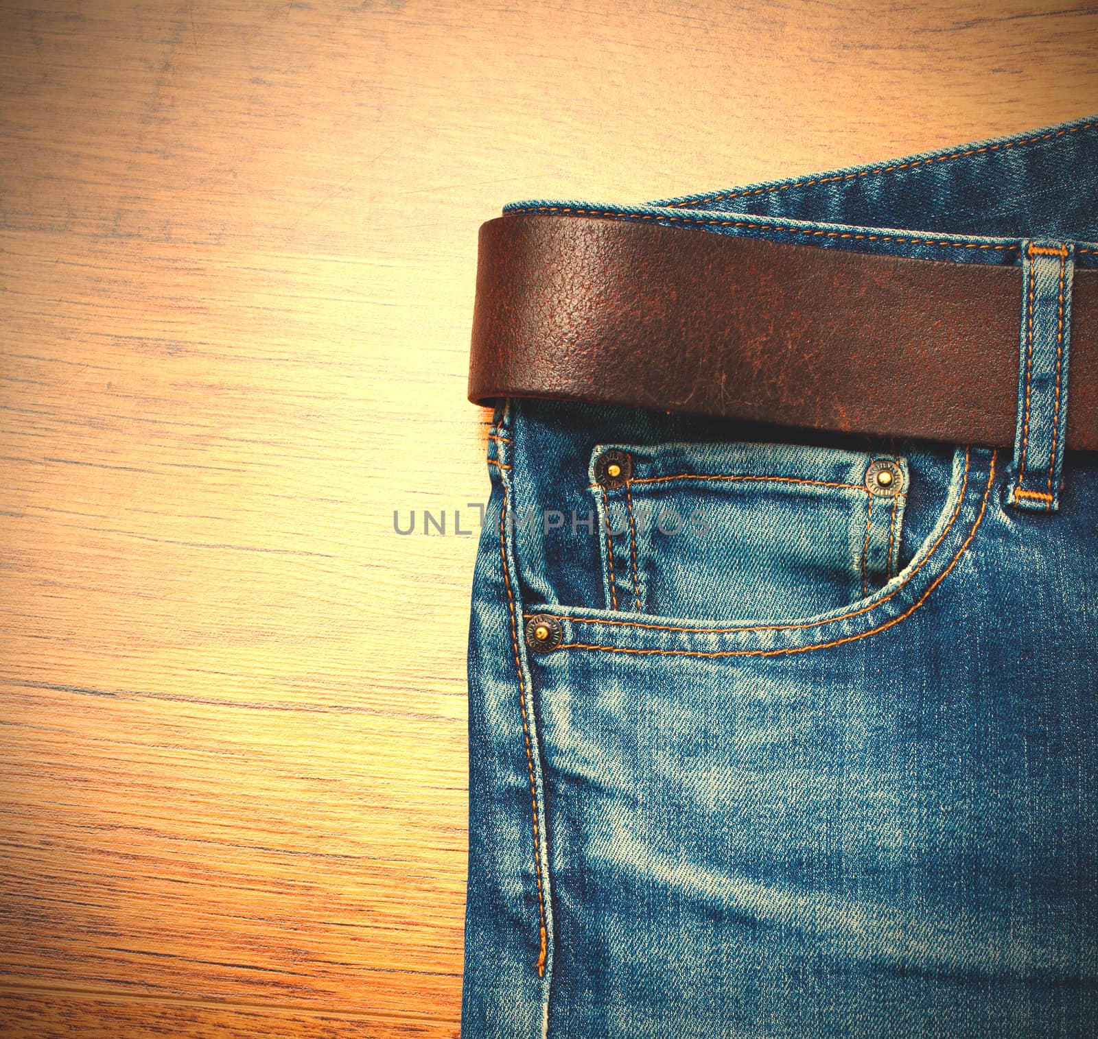 Aged jeans with a leather belt on wooden boards. copy space. Instagram image style