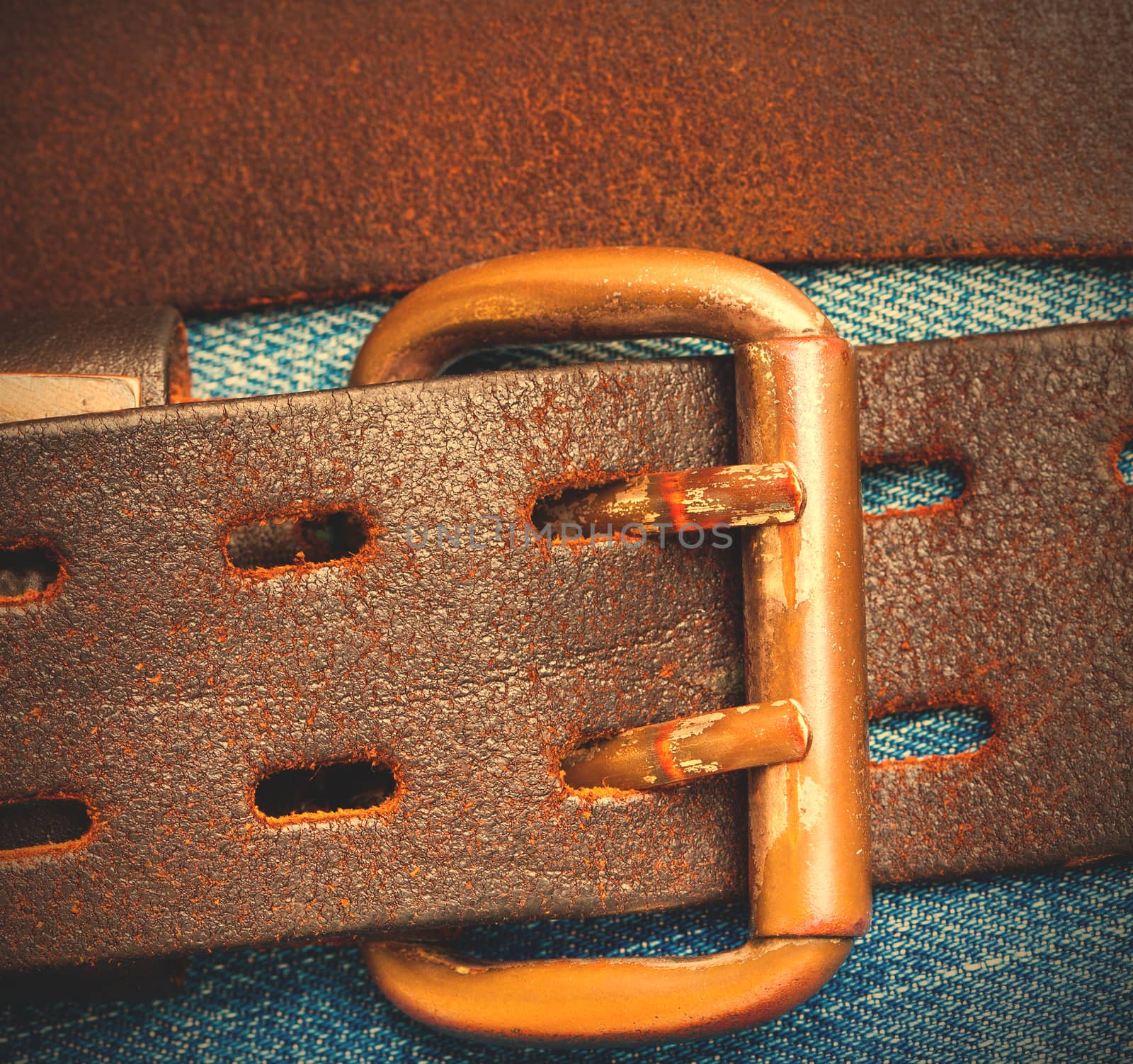 Vintage leather belt with a buckle on the background of denim. Instagram image style