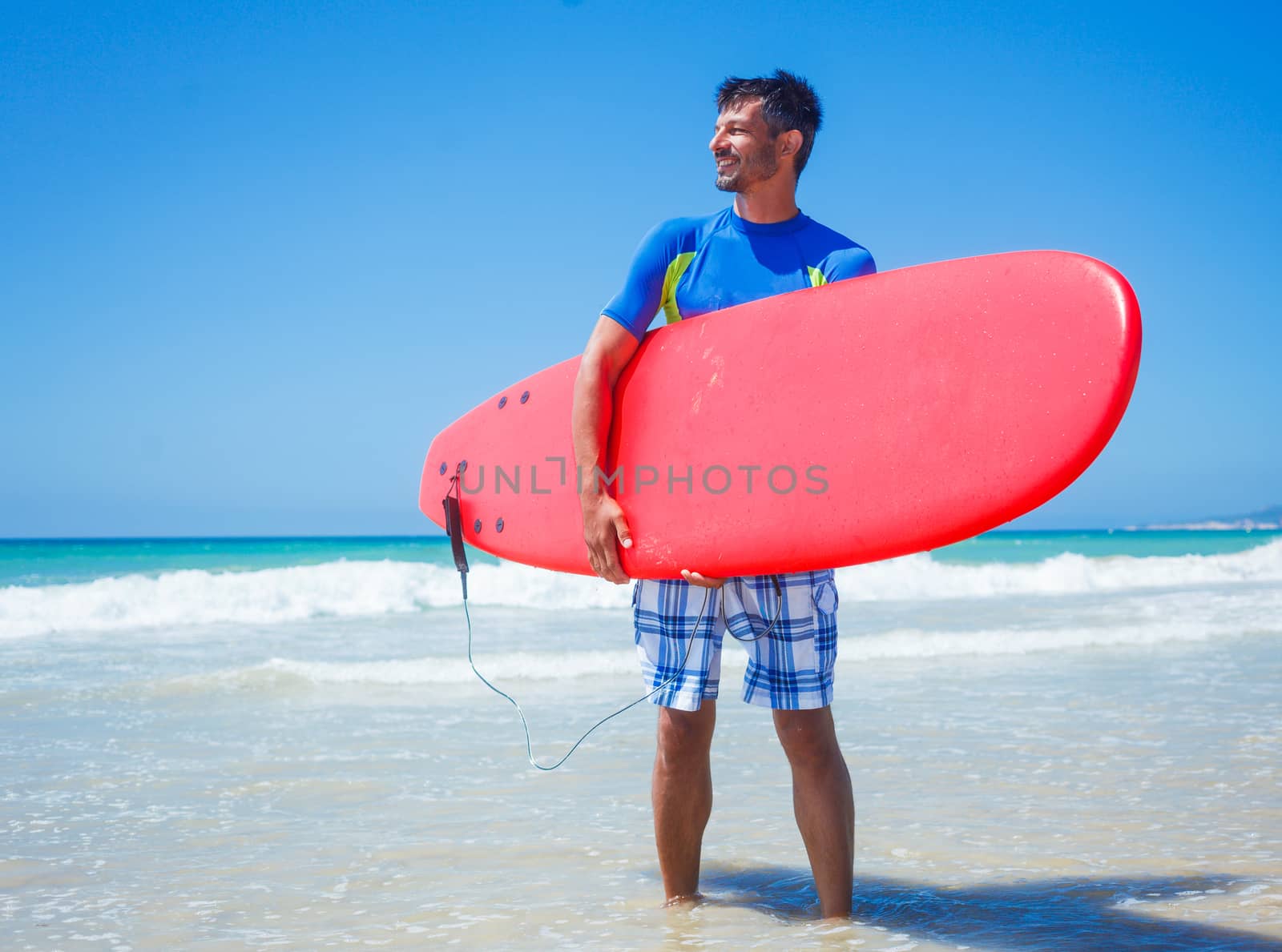 Strong young surf man at the beach with a surfboard.