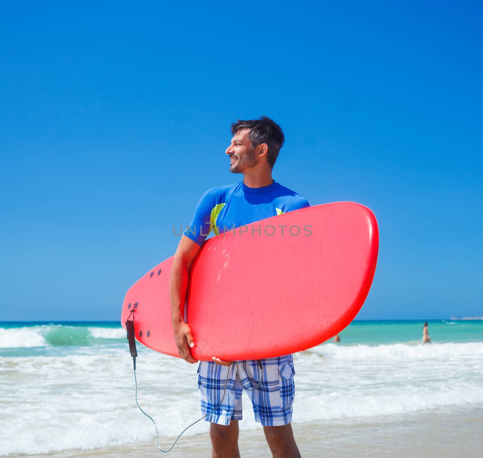 Strong young surf man at the beach with a surfboard.