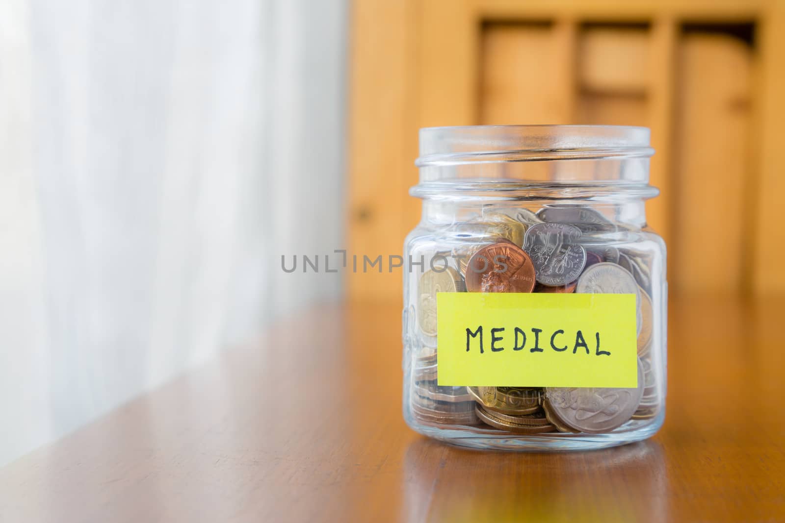 Glass bank with many world coins and  medical word or label on saving money jar