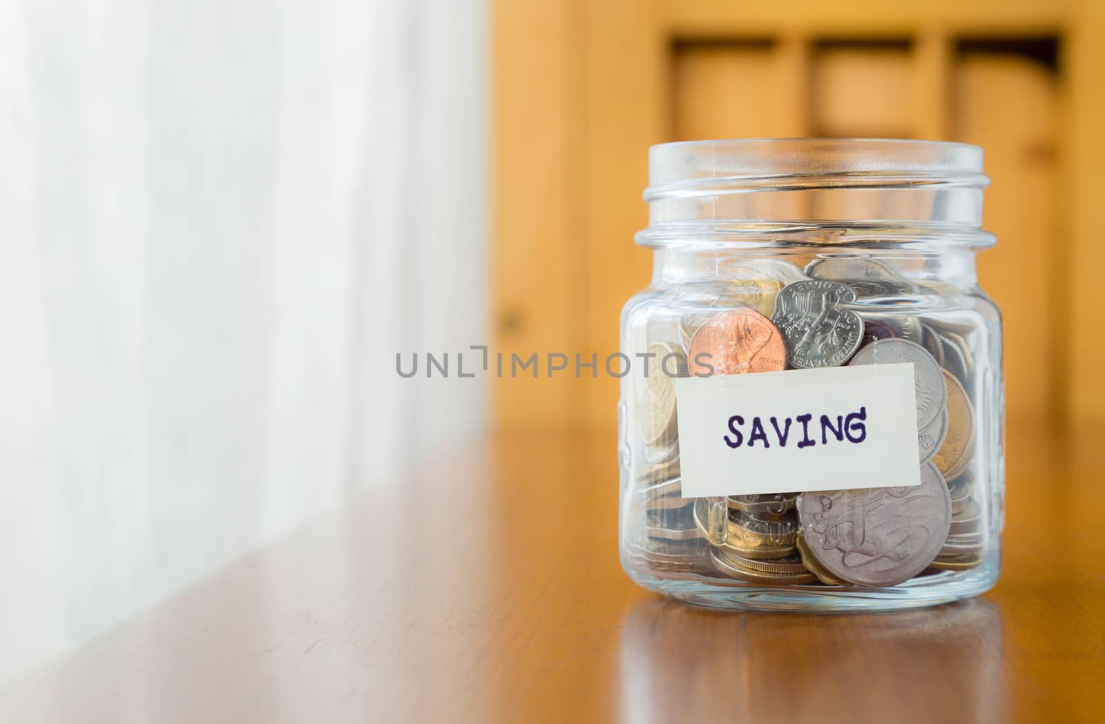 Glass bank with many world coins and  saving word or label on money jar, concept to financial planning