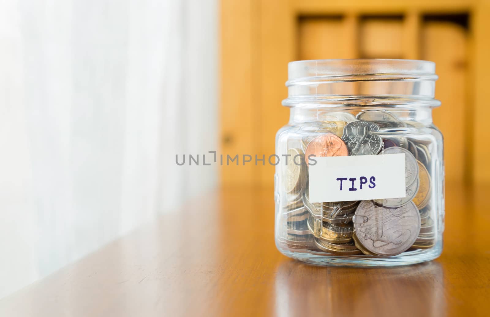 Glass bank with many world coins and  tips word or label on saving money jar