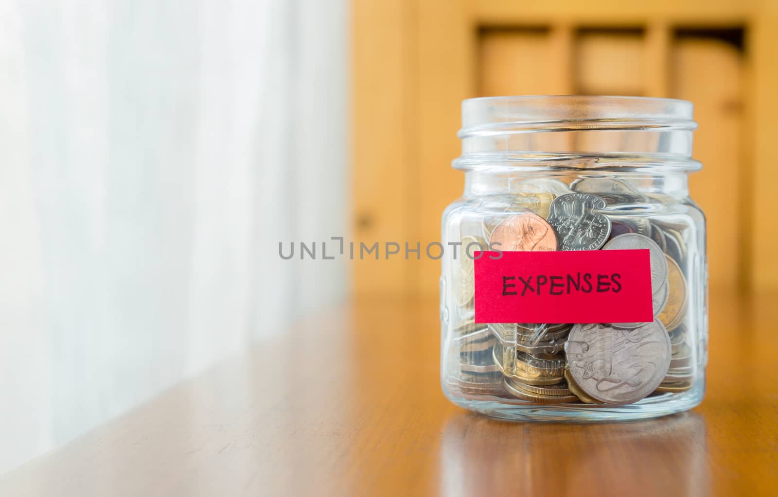 Glass bank with many world coins and  expenses word or label on saving money jar