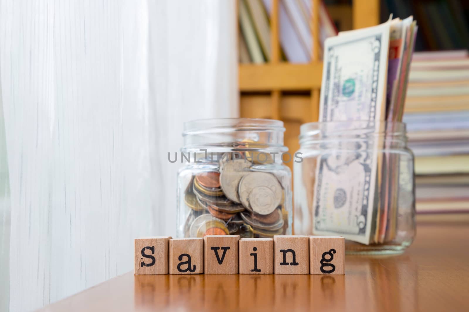 Saving word on rubber stamps place on table with coins and banknotes in money jars, concept to personal finance