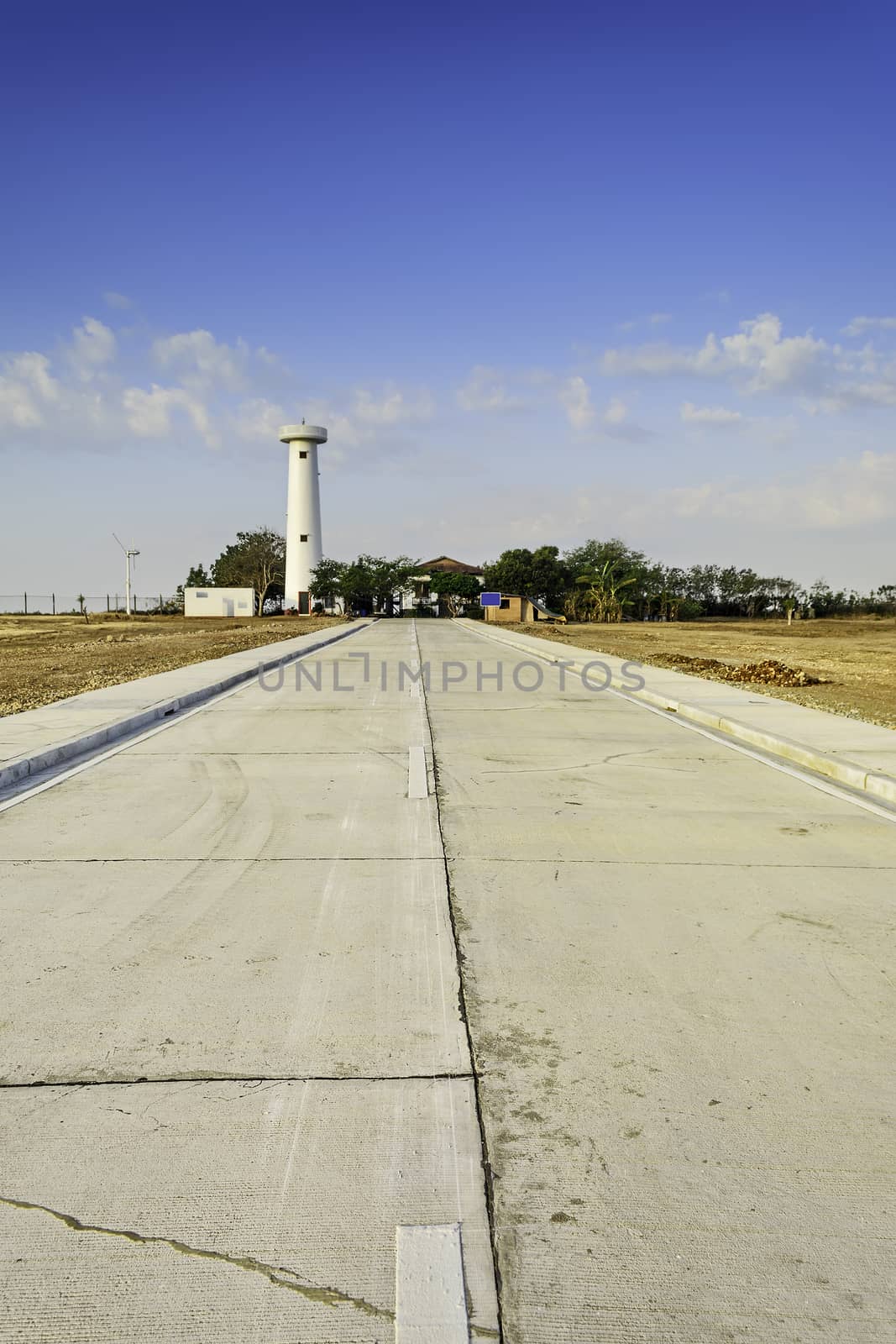 Newly built concrete road leading to a lighthouse undergoing restoration