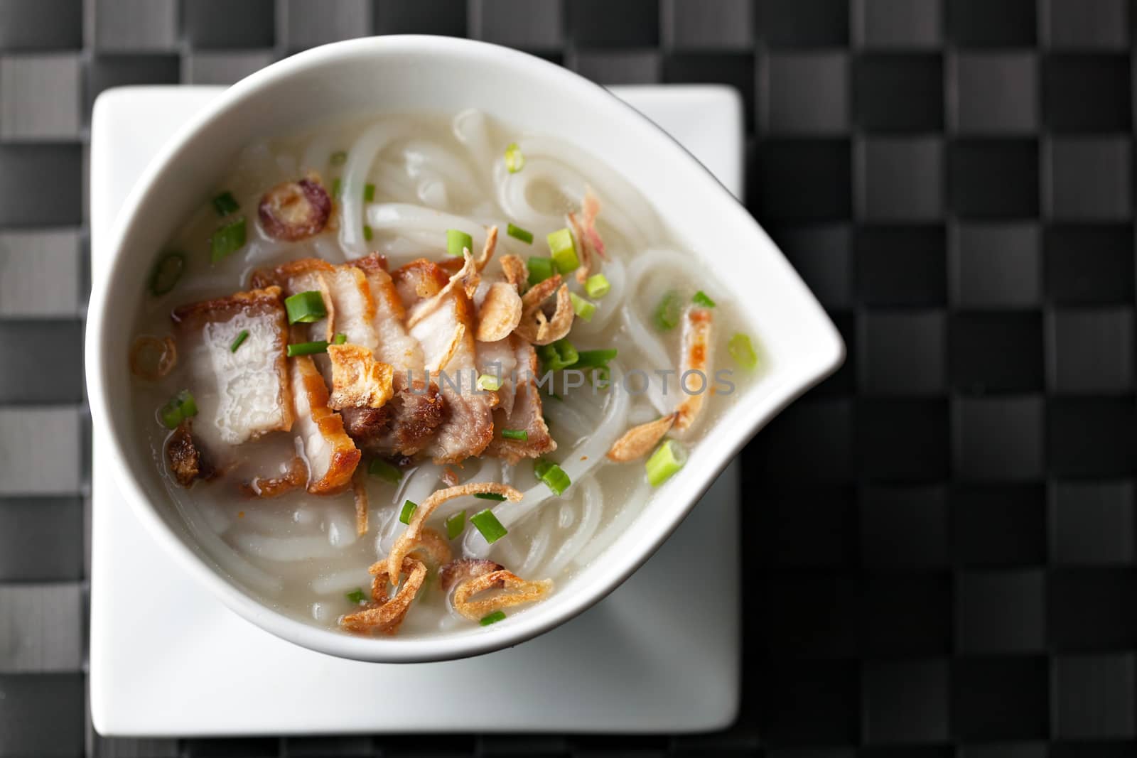 Closeup top down view of Thai style crispy pork rice noodle soup in a bowl with copy space.
