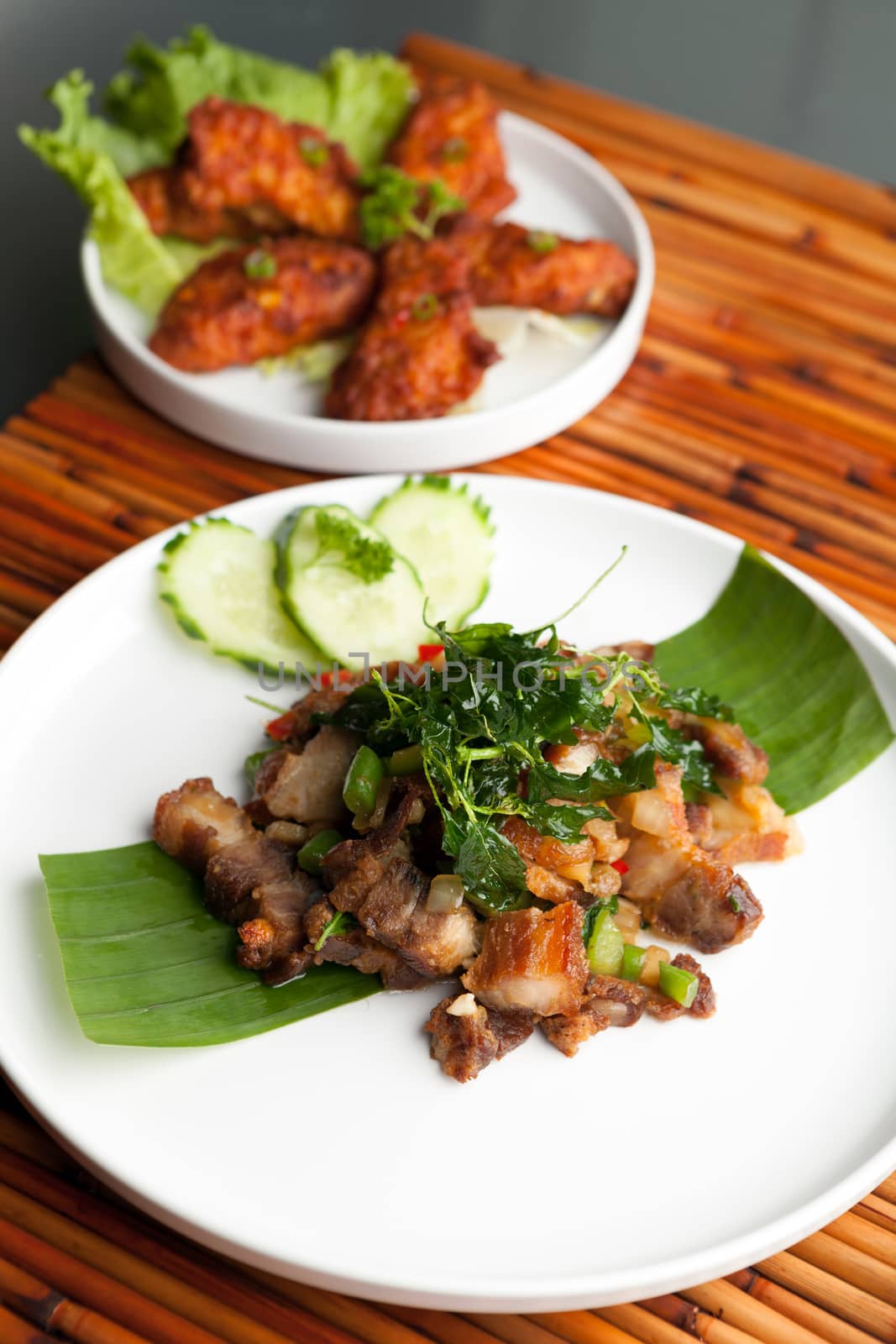 Traditional Thai crispy pork dish with green garnish.