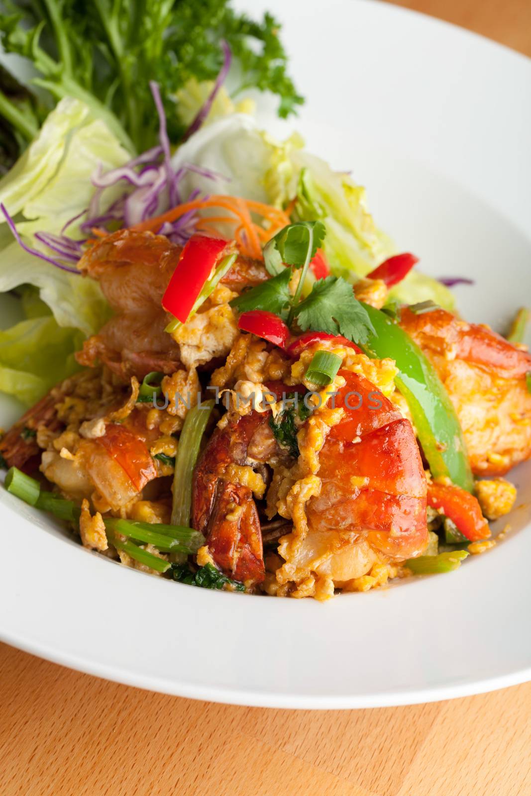 Thai jumbo shrimp salad on a round white plate. Shallow depth of field.