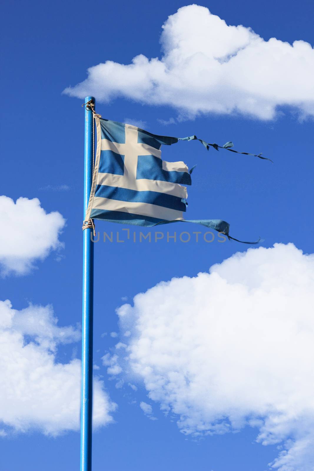 destroyed from the wind greek flag on a blue sky with clouds