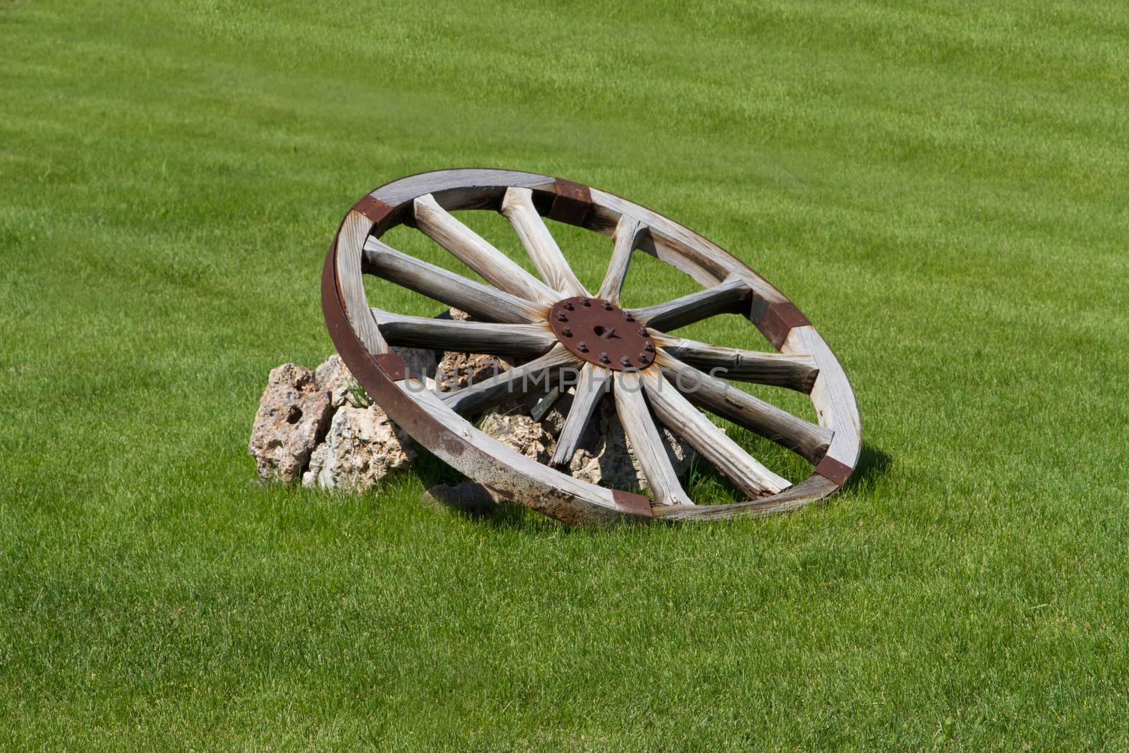 Old wooden wheel on grass.