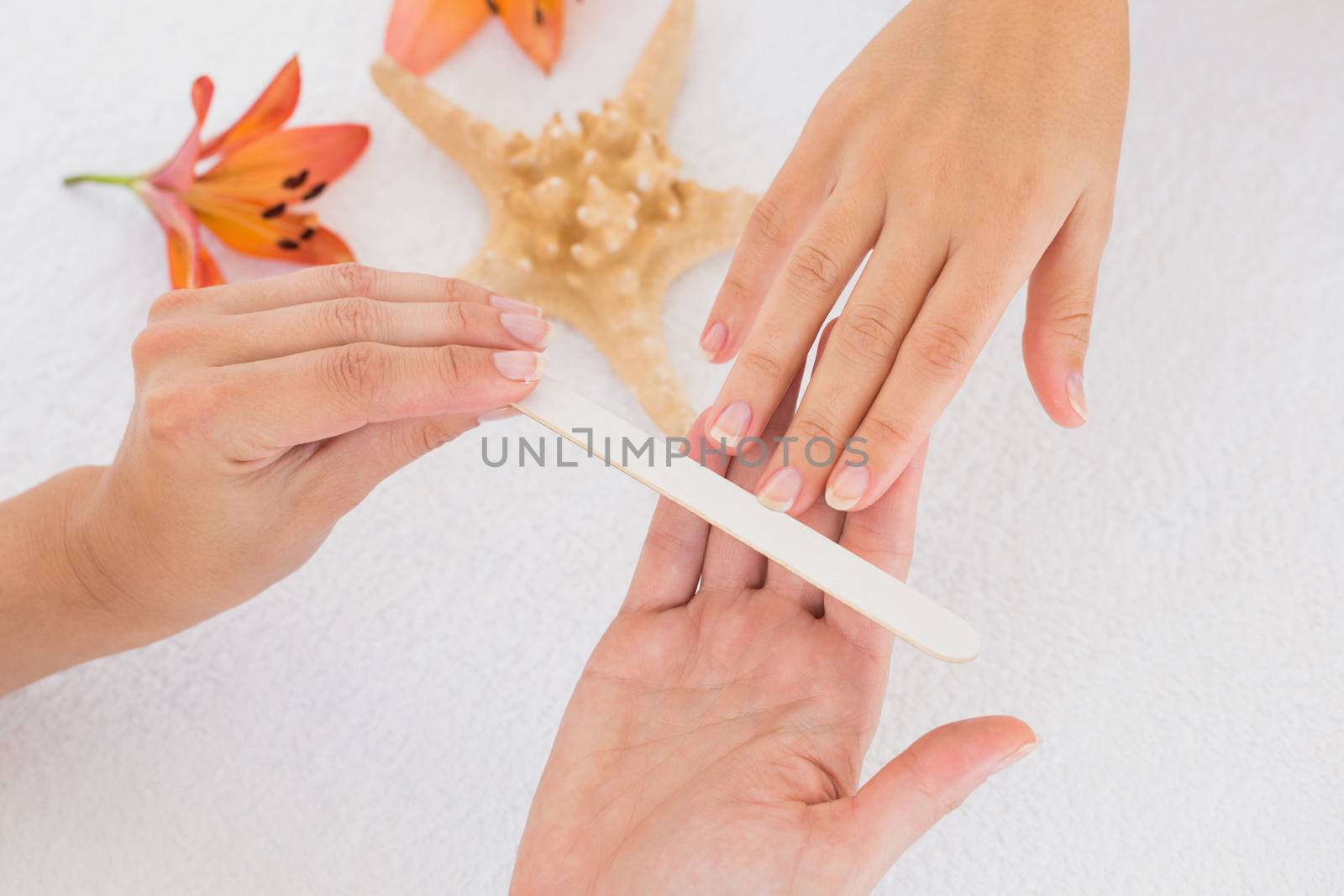 Close up of beautician filing female client's nails at spa beauty salon
