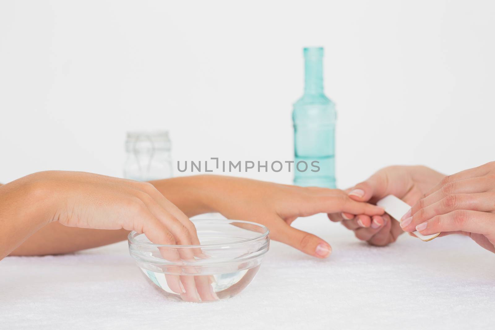 Close up of beautician filing female client's nails at spa beauty salon