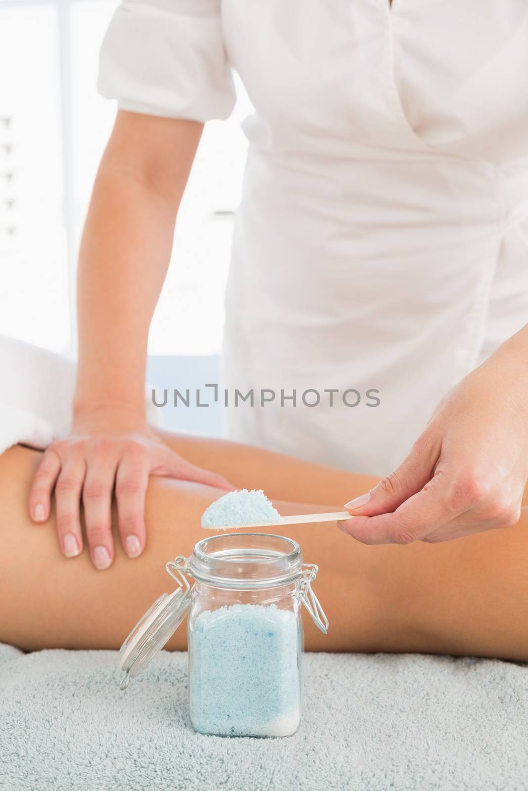 Close up of a beauty therapist using salt scrub at spa center