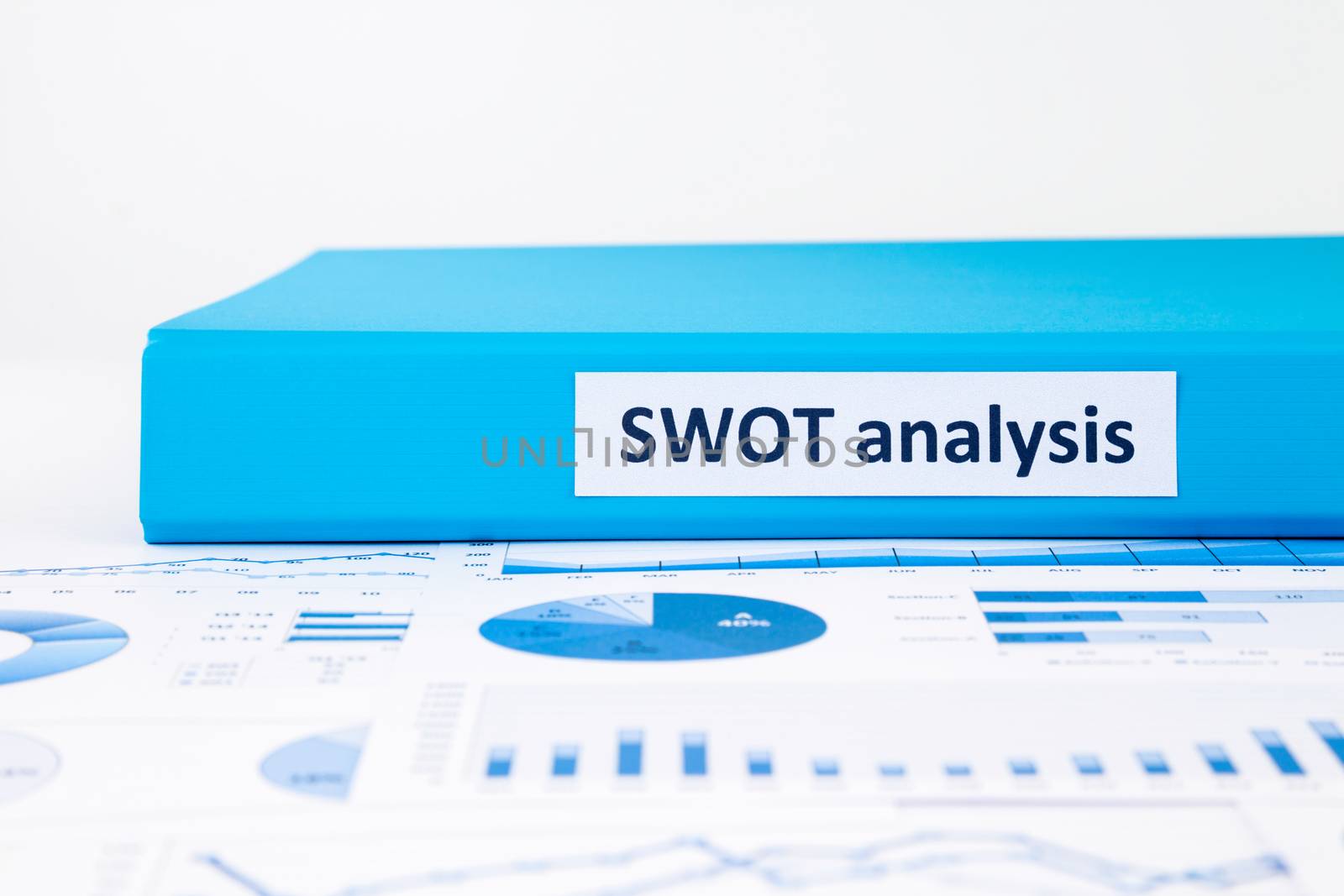 Blue document binder of SWOT analysis place on business graph report concept to evaluate and planning projects