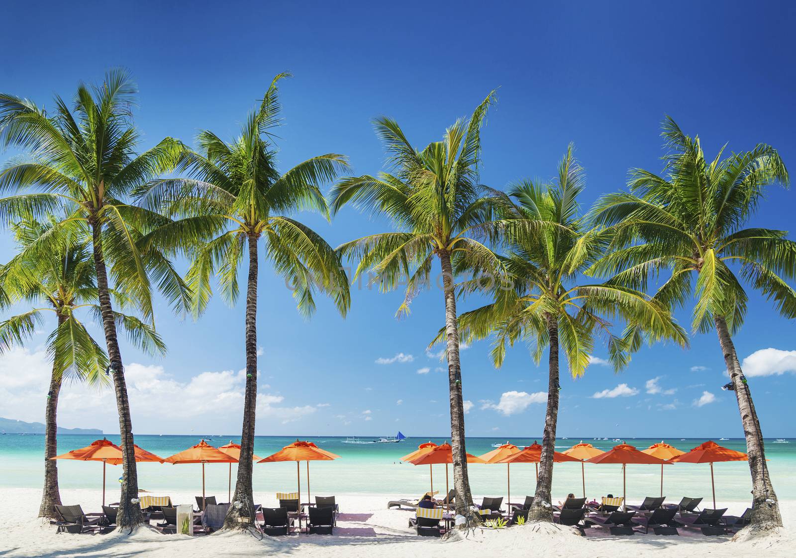 white beach lounge bar chairs and umbrellas on boracay tropical island in philippines