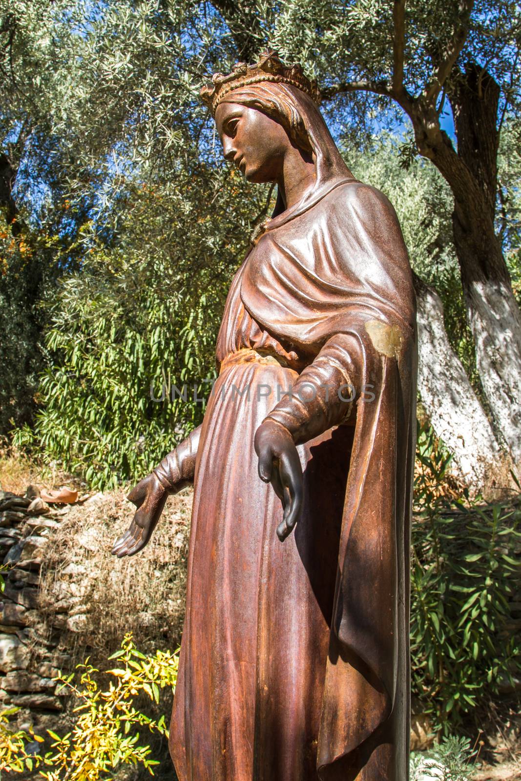 Side view of bronze statue of holy Virgin Mary in natural place.