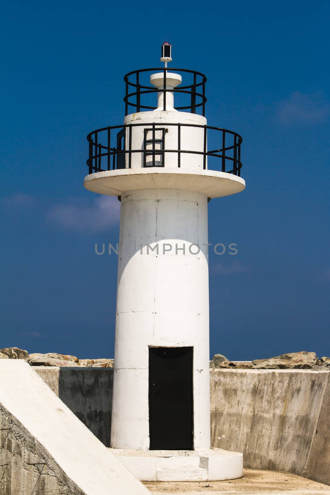 Close up view of white lighthouse on clear, blue sky.