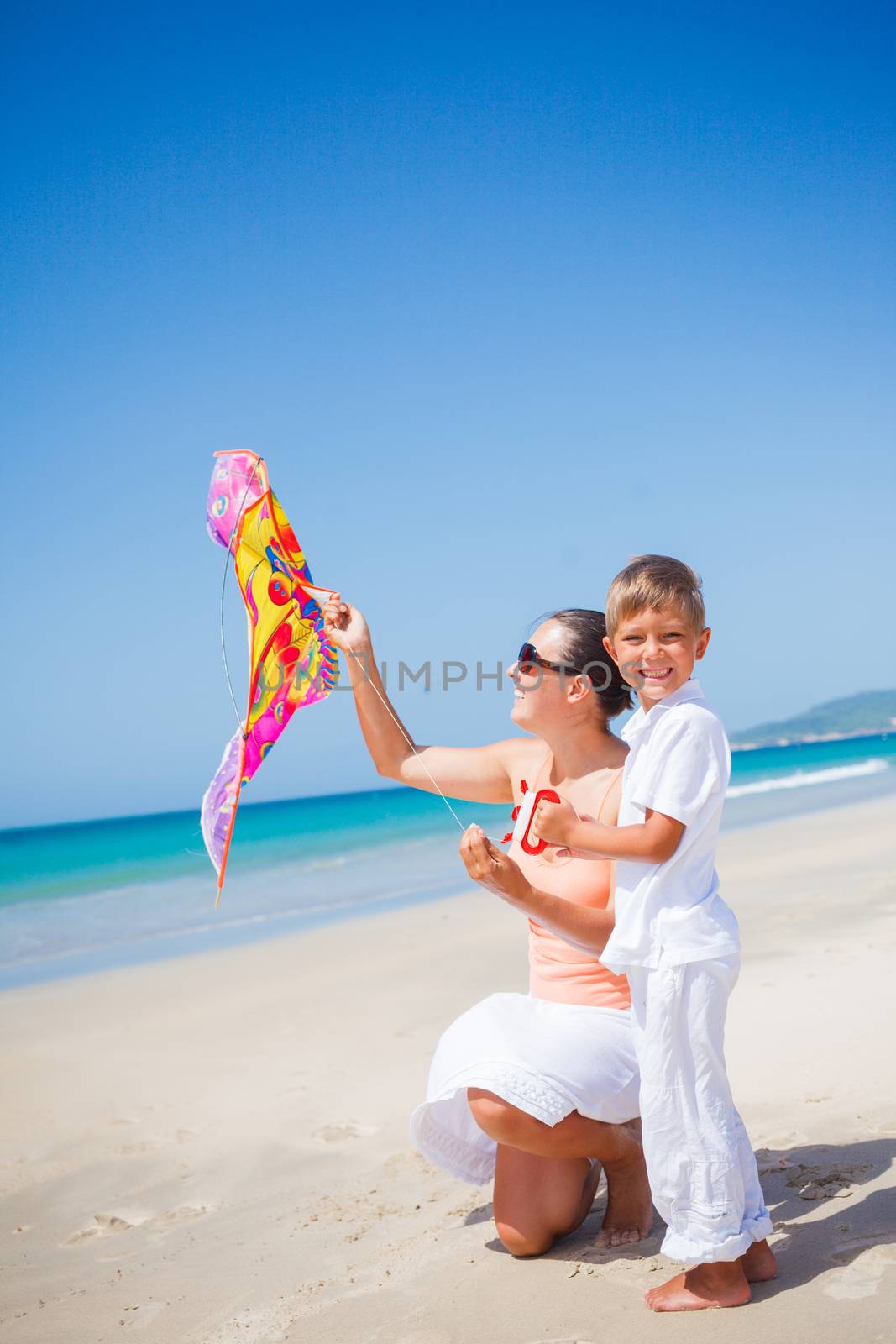 Summer vacation - Cute boy with his mother flying kite beach outdoor.