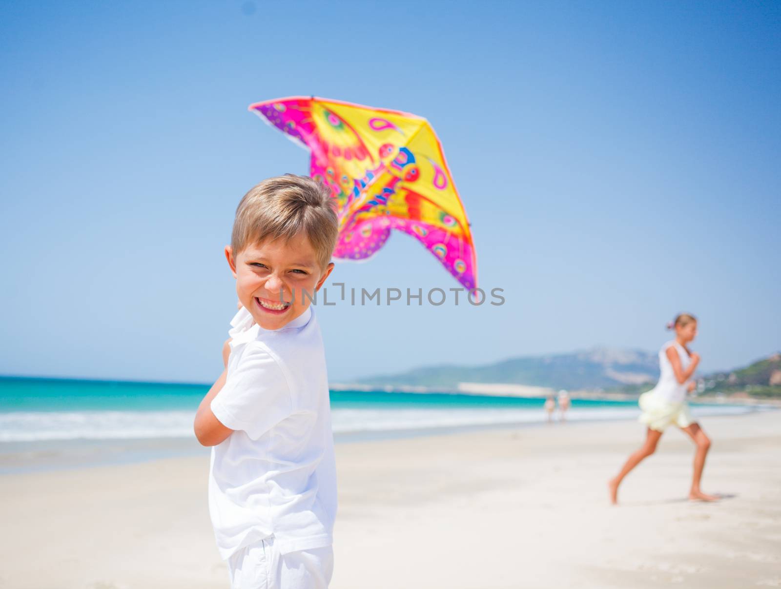 Summer vacation - Cute boy and girl flying kite beach outdoor.