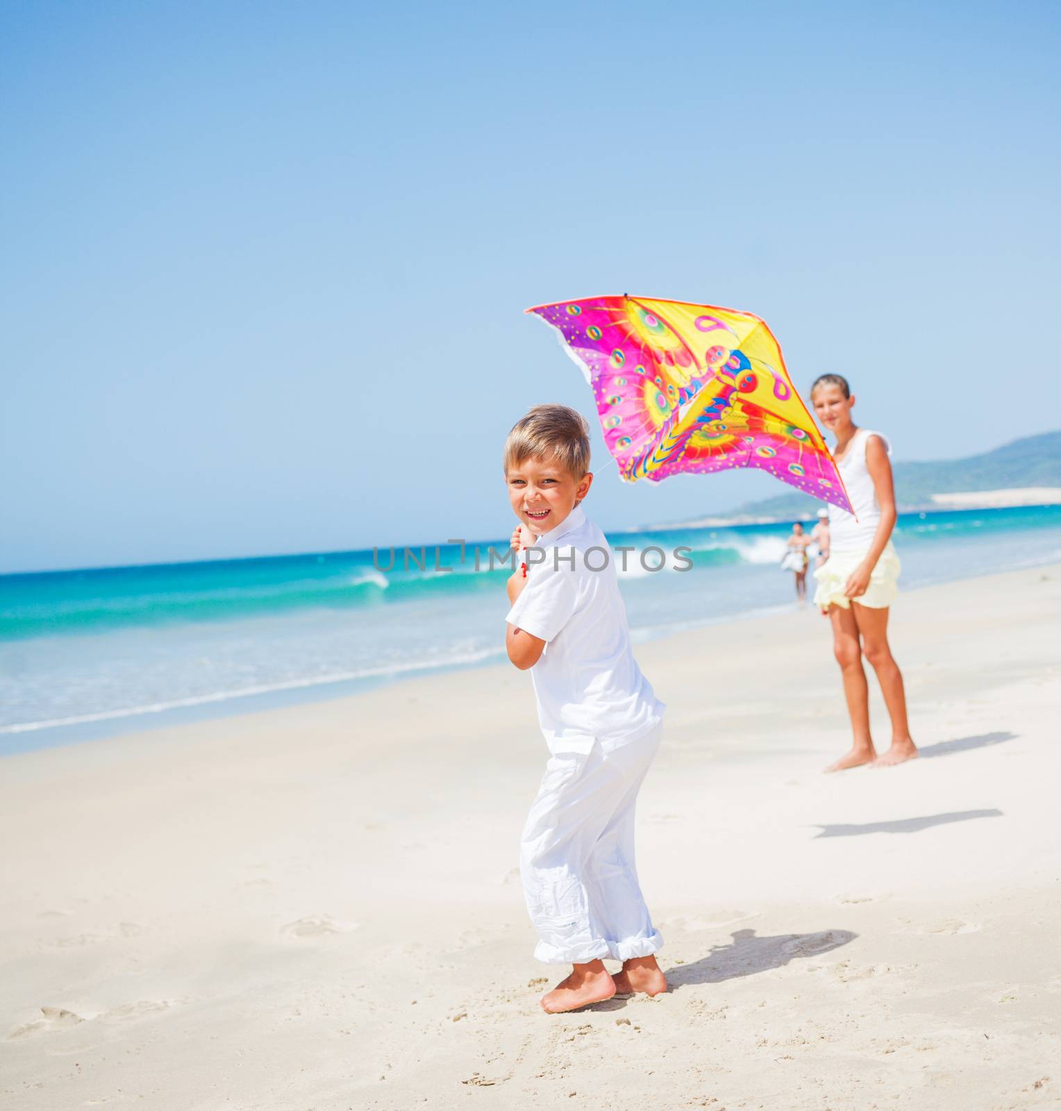 Summer vacation - Cute boy and girl flying kite beach outdoor.