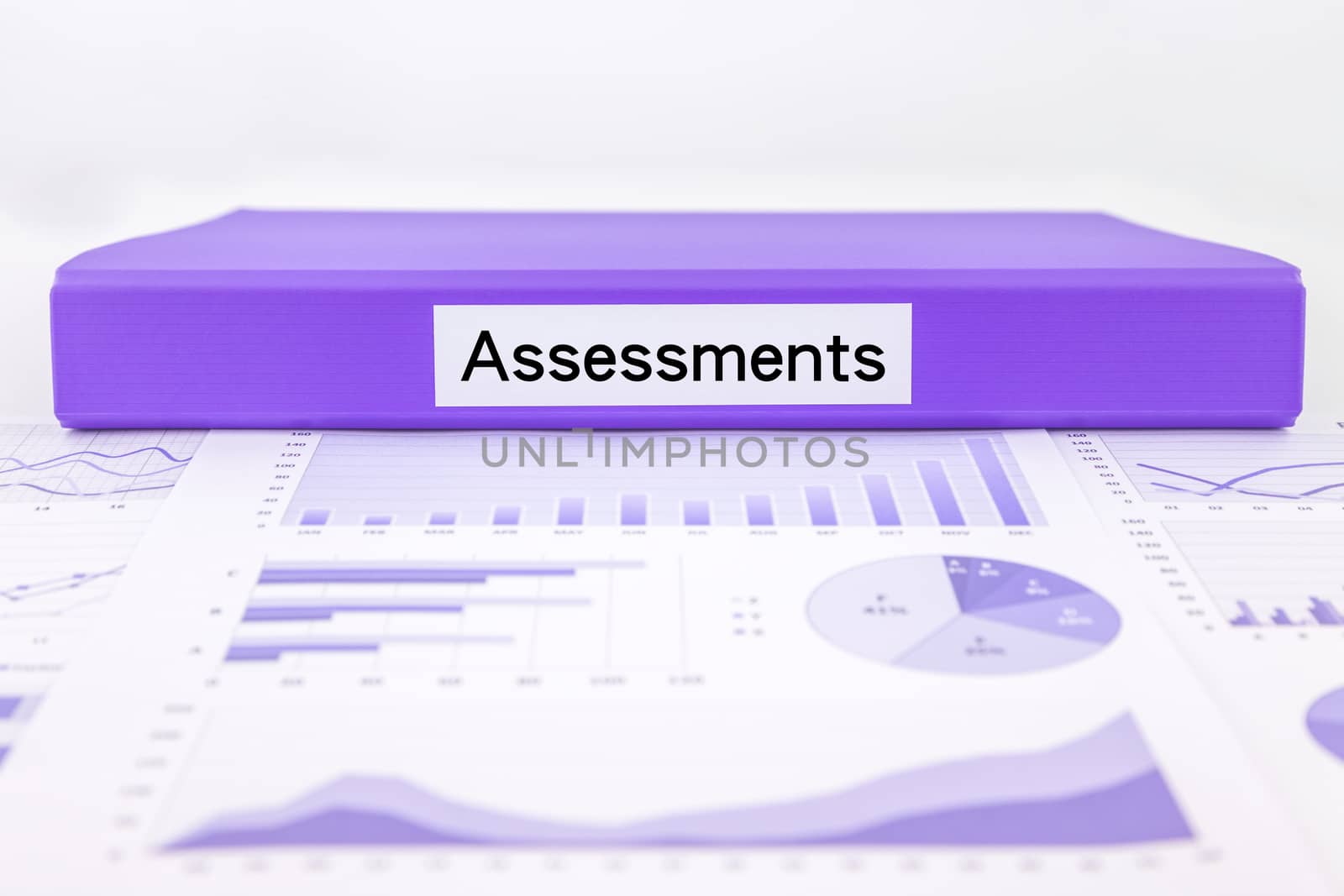 Purple document binder with assessments word place on graphs, charts and data analysis of business evaluation