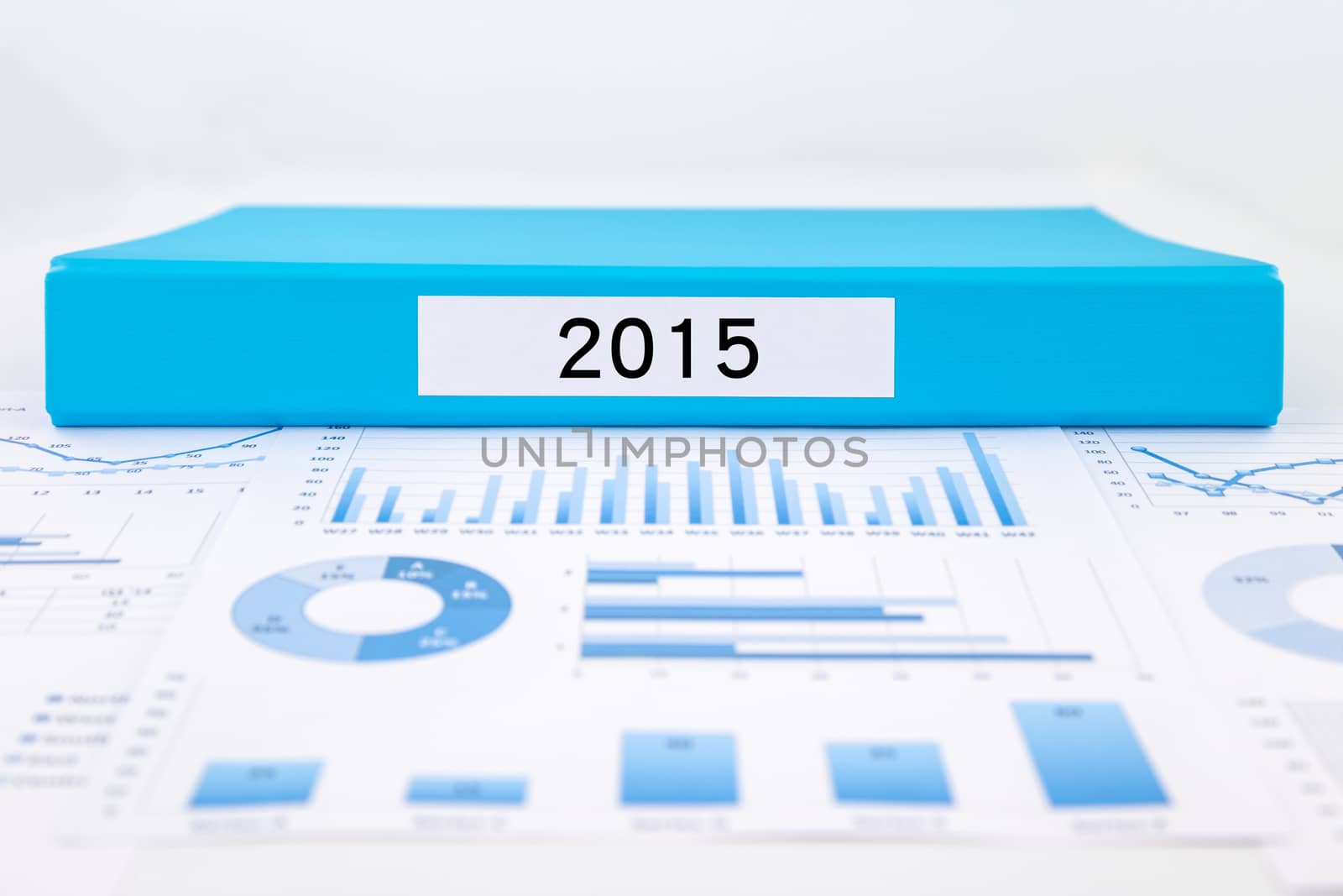 Blue document binder with year number 2015 place on graphs and charts of financial analysis reports