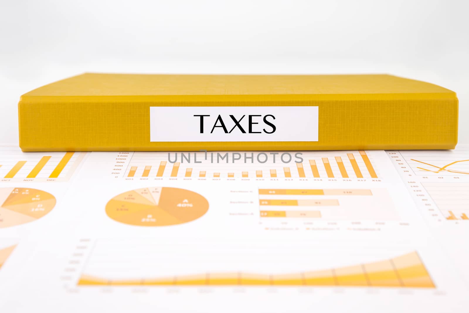 Yellow document binder with TAXES word place on graphs analysis and financial reports