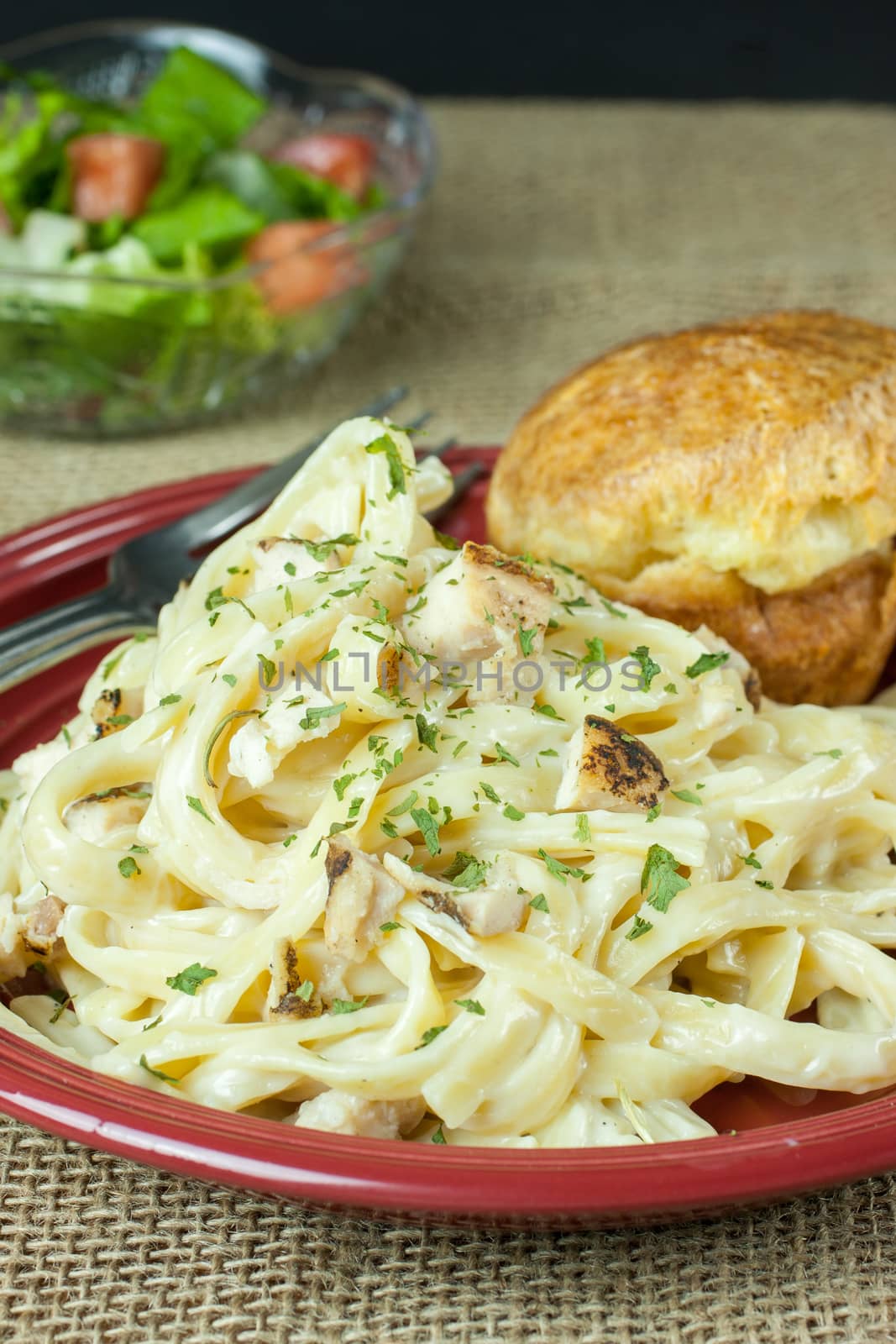 Chicken Fettucine Alfredo with a classic popover and a salad on a burlap cloth.