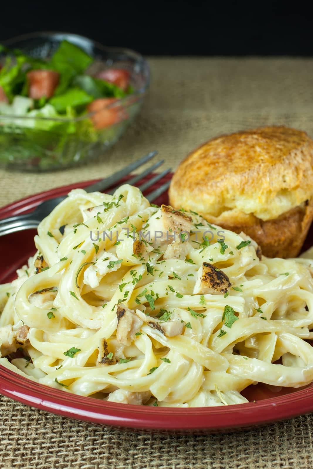 Chicken Fettucine Alfredo with a classic popover and a salad on a burlap cloth.