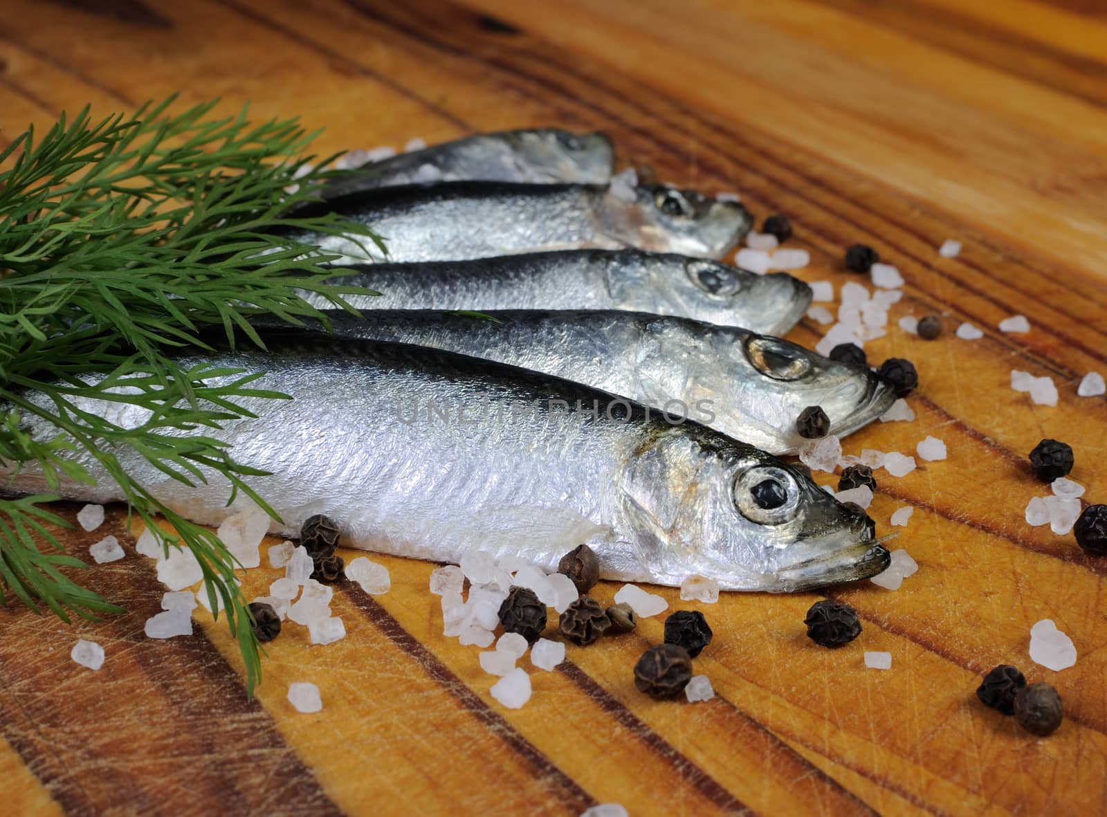 Salted sprats with salt and pepper on the board