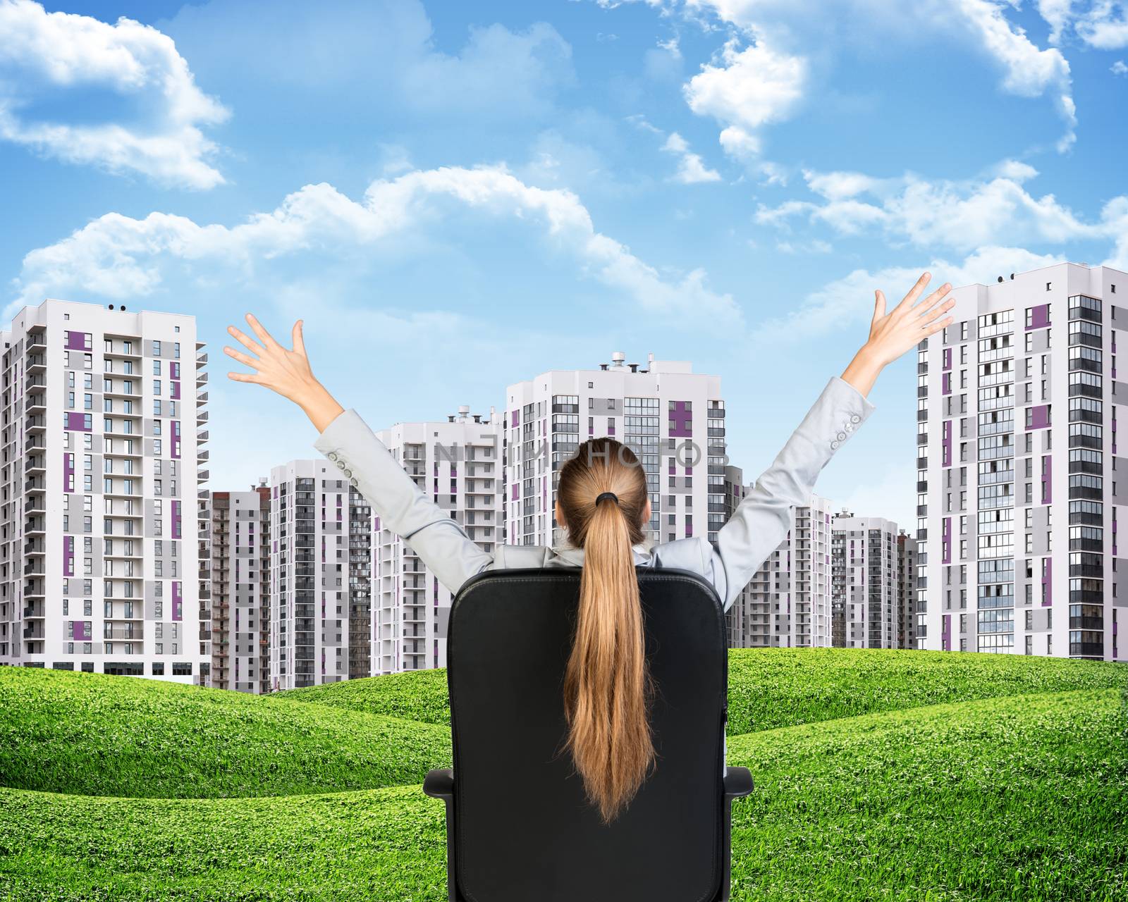 Businesswoman sitting on office chair with her hands outstretched. Green hills with buildings and sky as backdrop