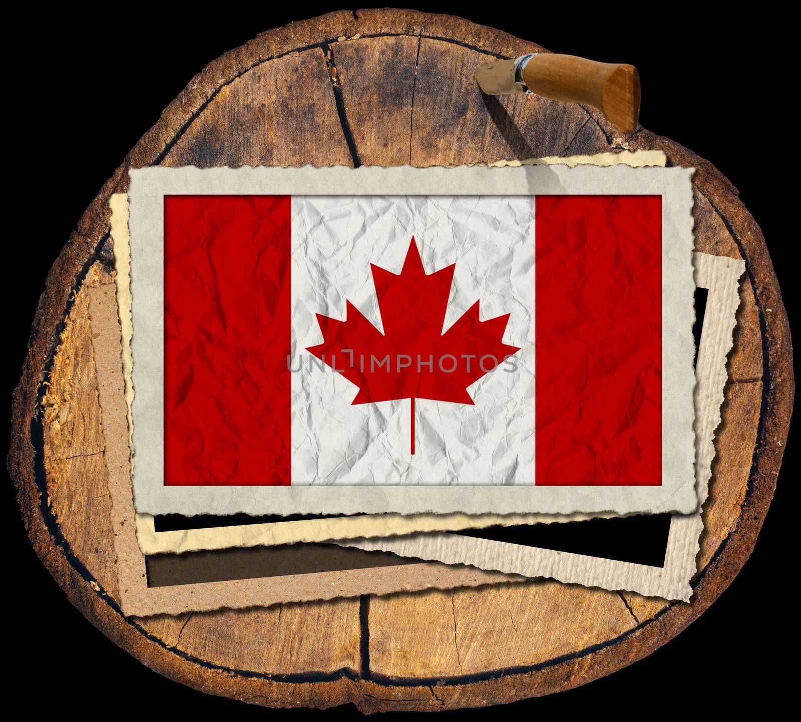 Flag of Canada in a old photo frame on a section of tree trunk isolated on black background