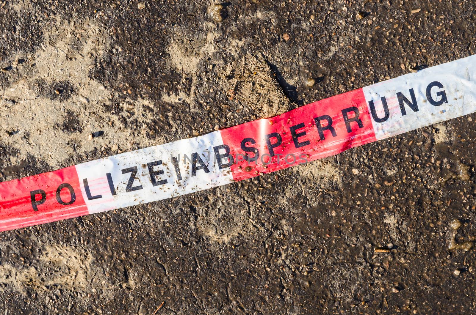 German police line red white tape torn and trampled on street asphalt dirt after procession or demonstration